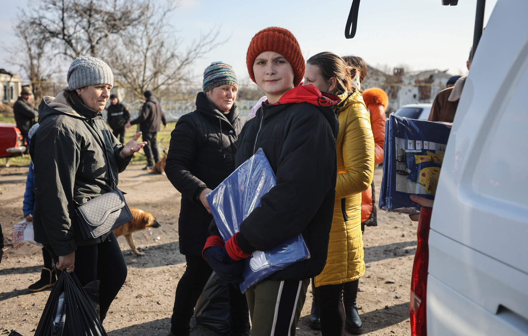 A young person in Ukraine carrying bedding they received from MCC