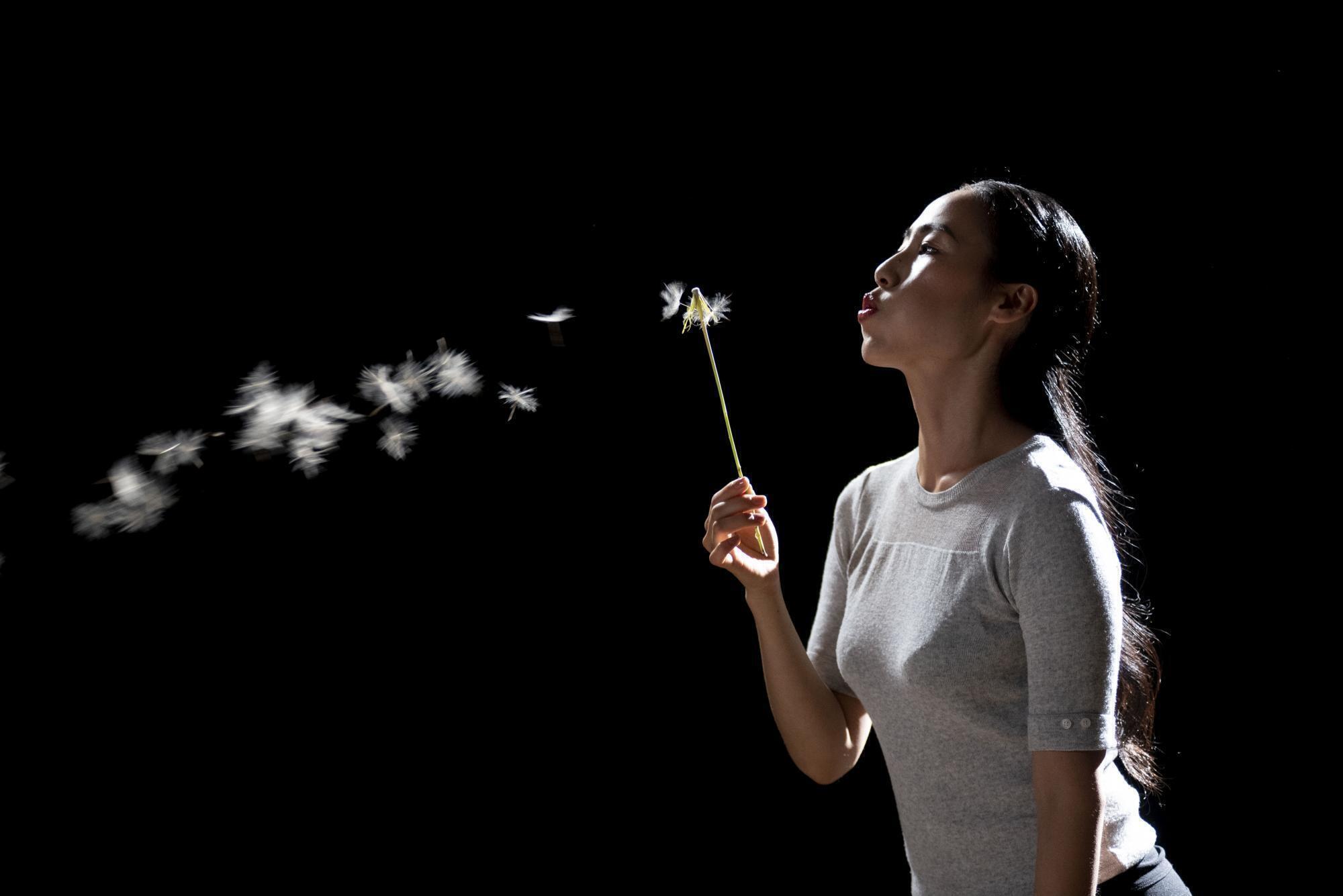 A woman blowing on a dandelion