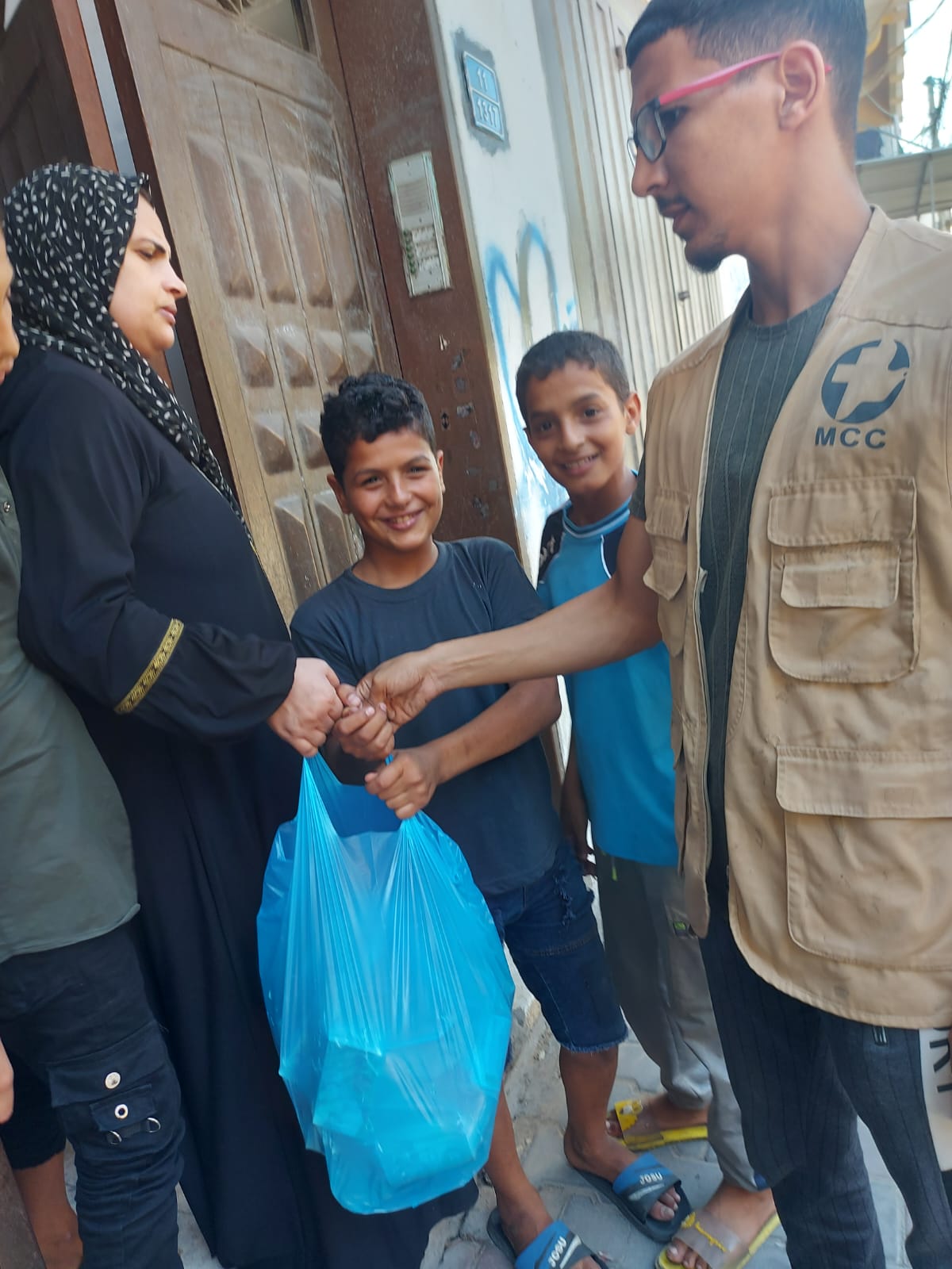 A man handing relief supplies to a woman and two boys