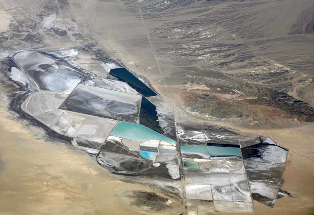 Looking from above at the scarred ground due to lithium mining and unnaturally clear blue pools of liquid.