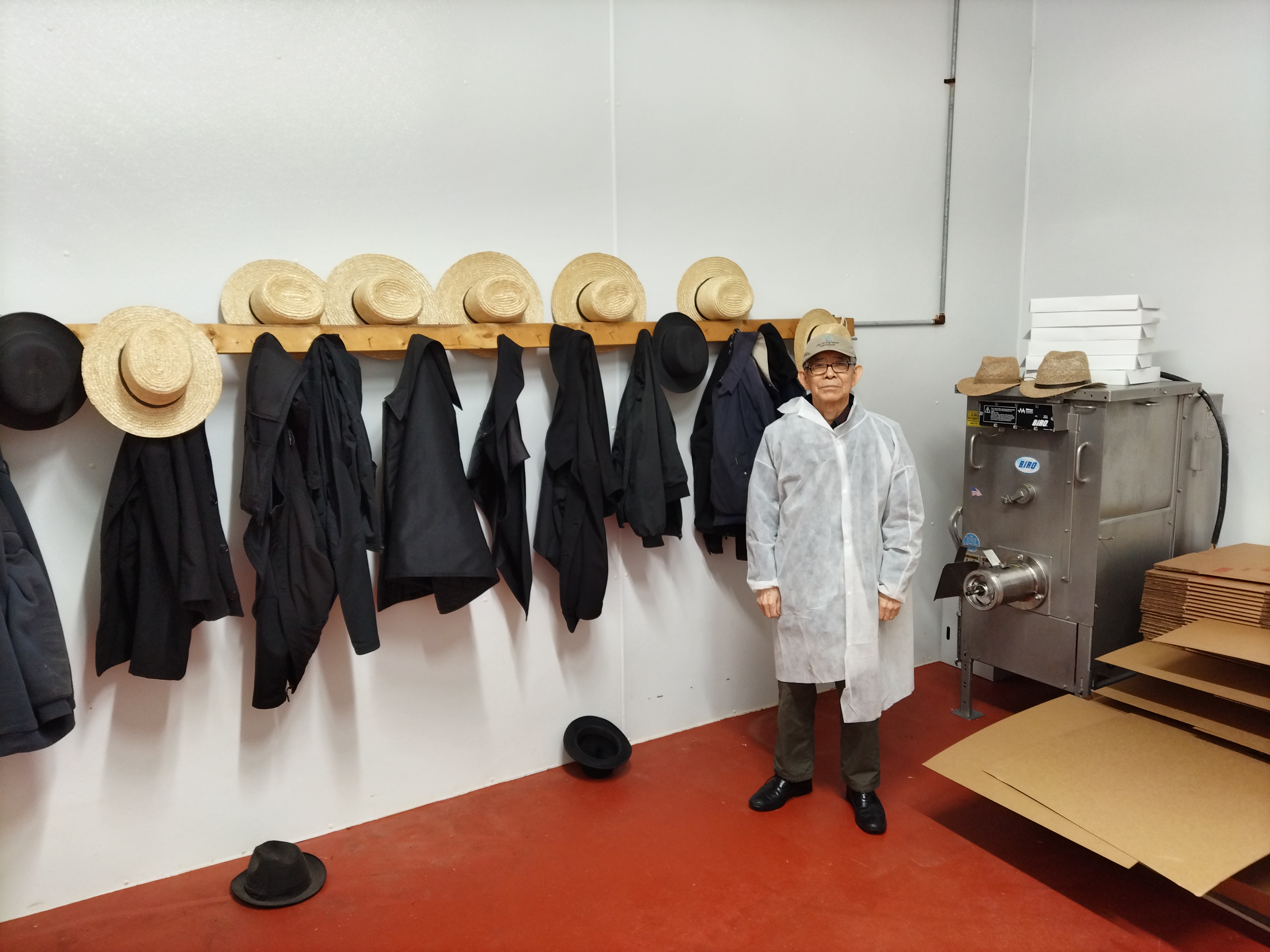 David Suh stands next to the hats and coats of Old Order Amish volunteers at the New Holland meat canning site. 