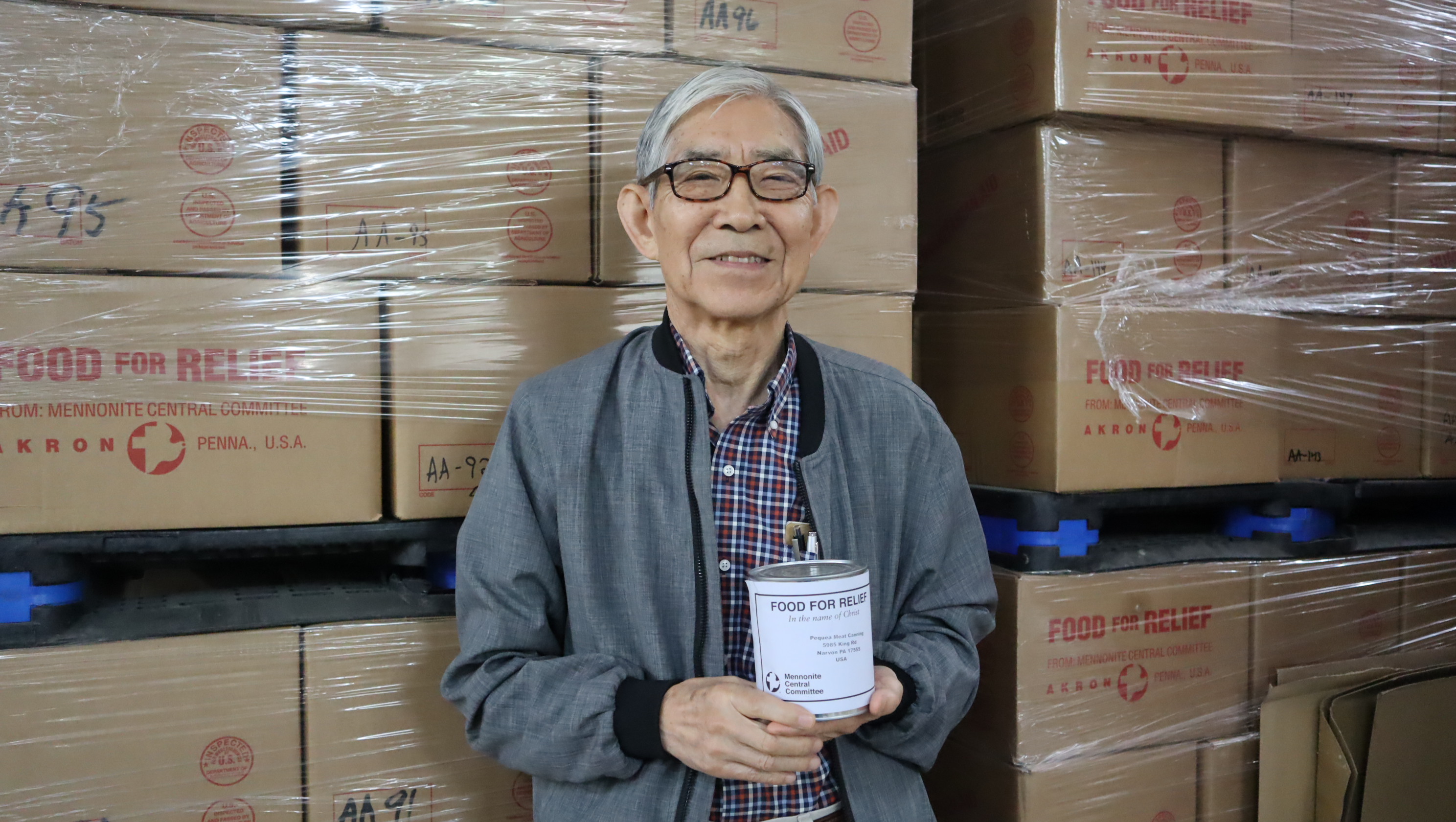 David Suh holds canned meat at the Material Resources Center. 
