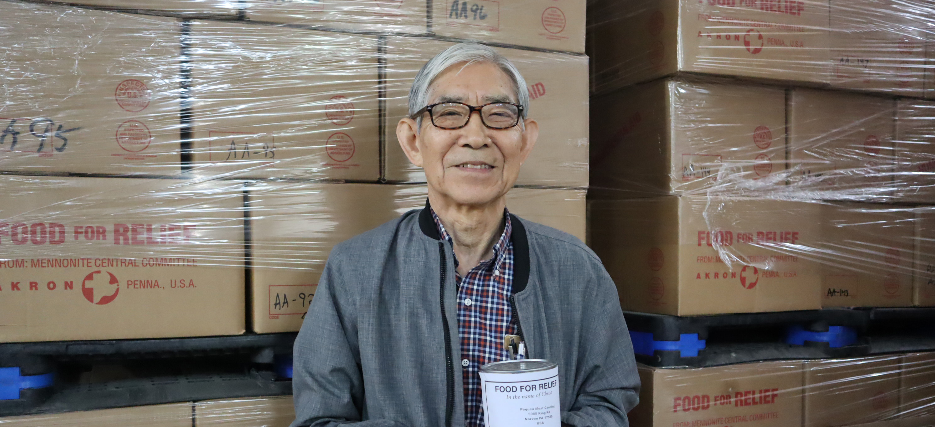 David Suh holds canned meat at the Material Resources Center. 