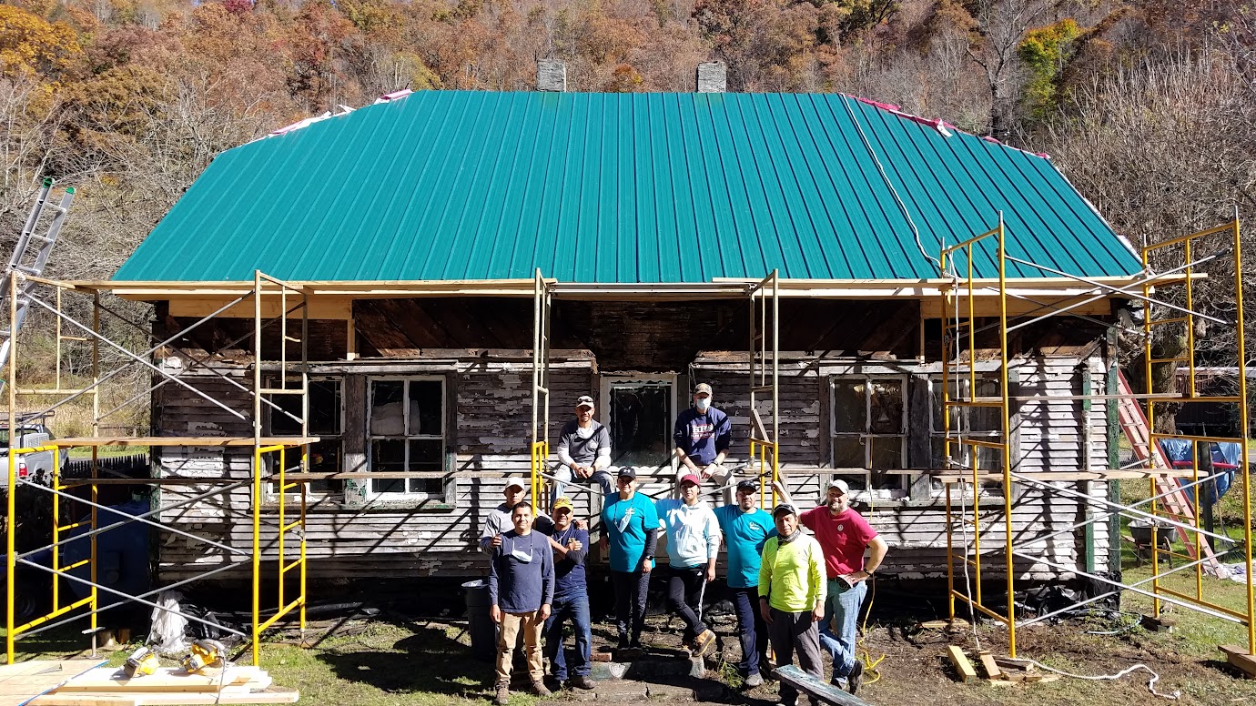 group of people stand in front of house with new metal roof