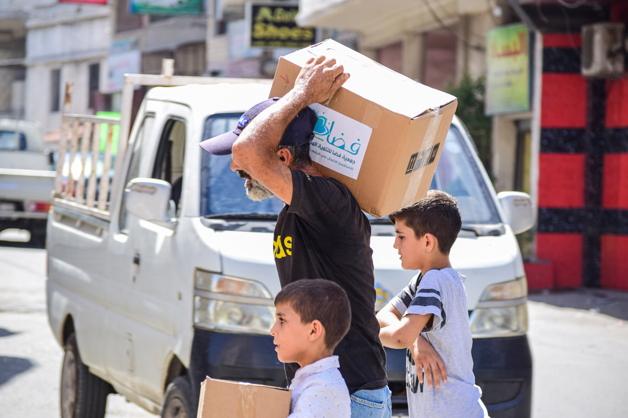 A man and two children carrying relief supplies