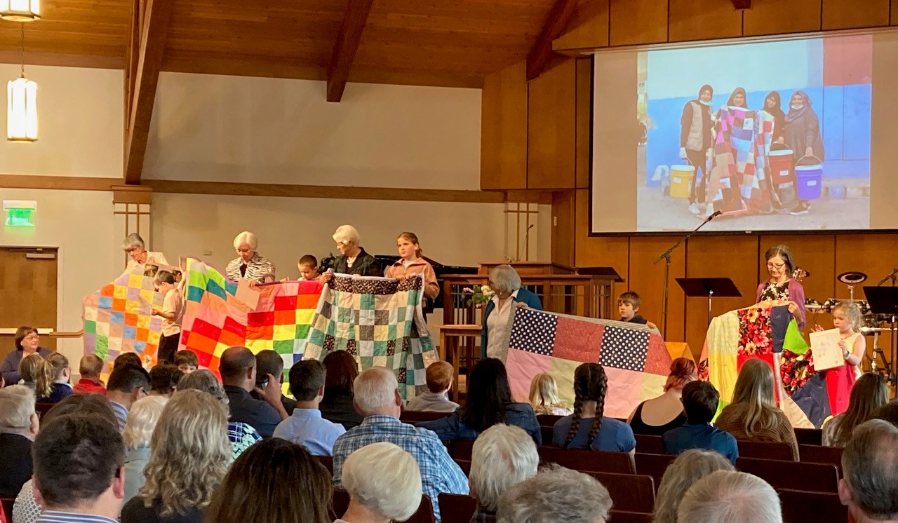 Five children who participated in the "Design a Cheerful Comforter" project present their finished comforters to the congregation at Lindale Mennonite Church. (Photo courtesy of Lois King)