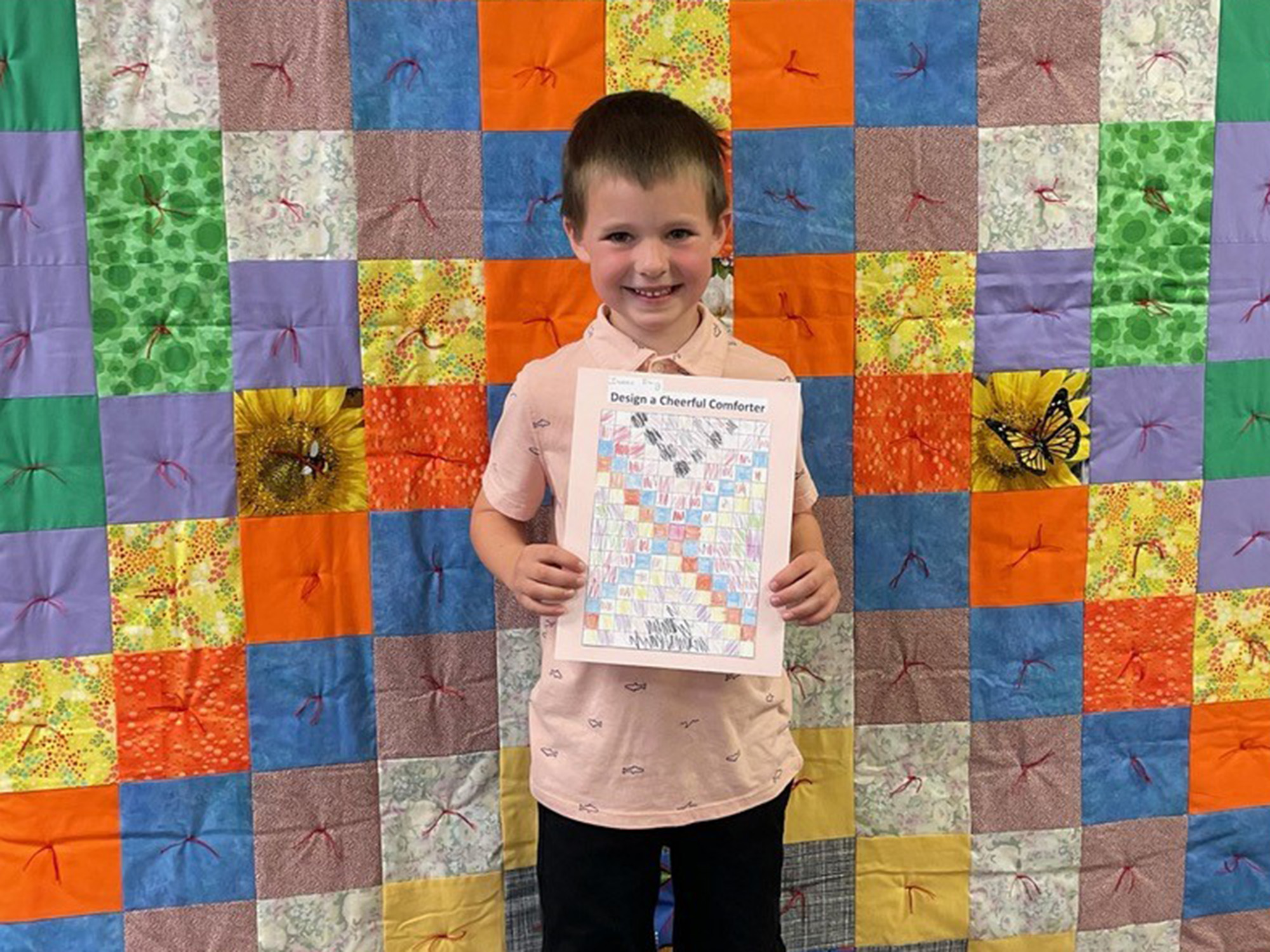 Kid standing in front of a quilt.