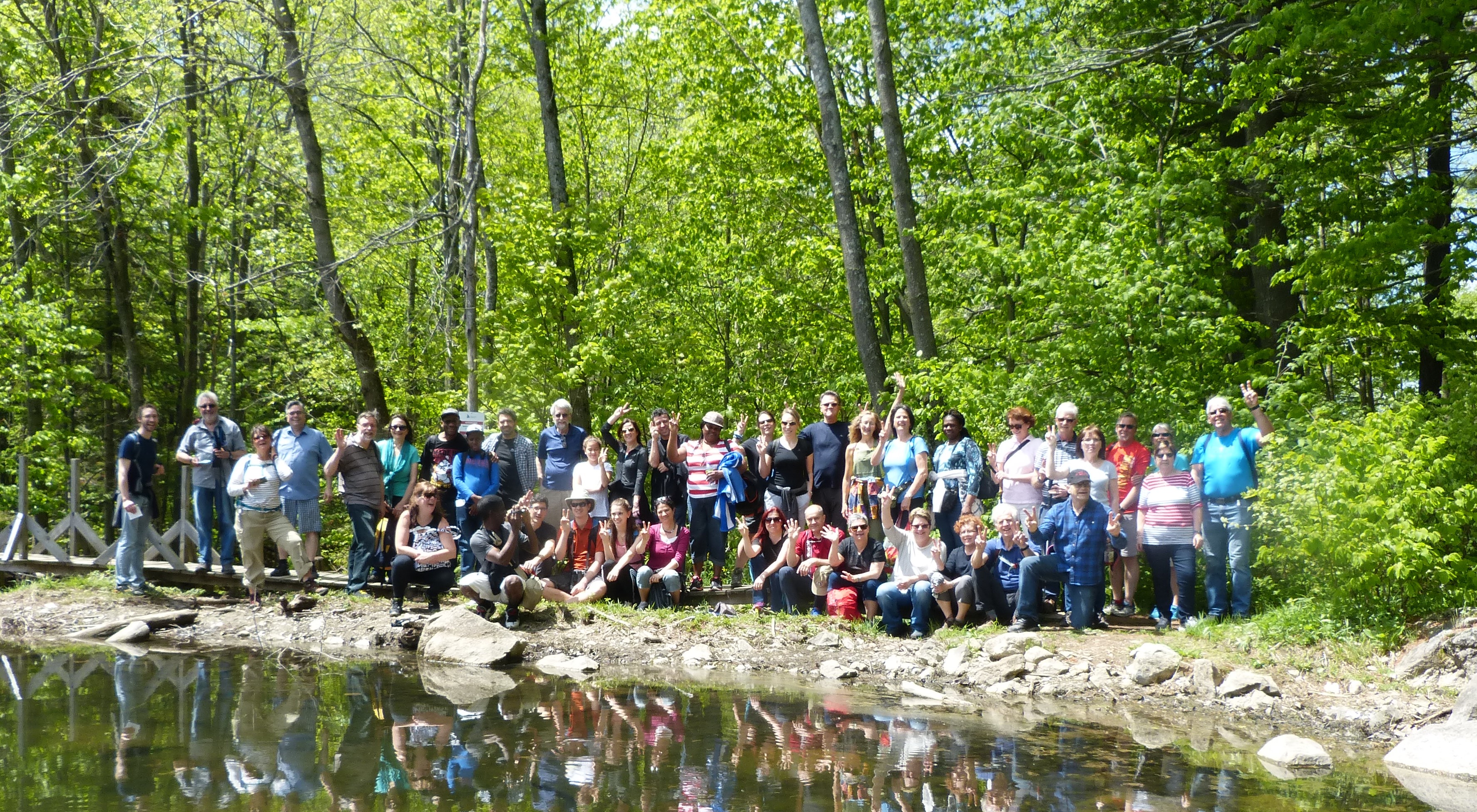 A group of people standing for a photo by water in a forest