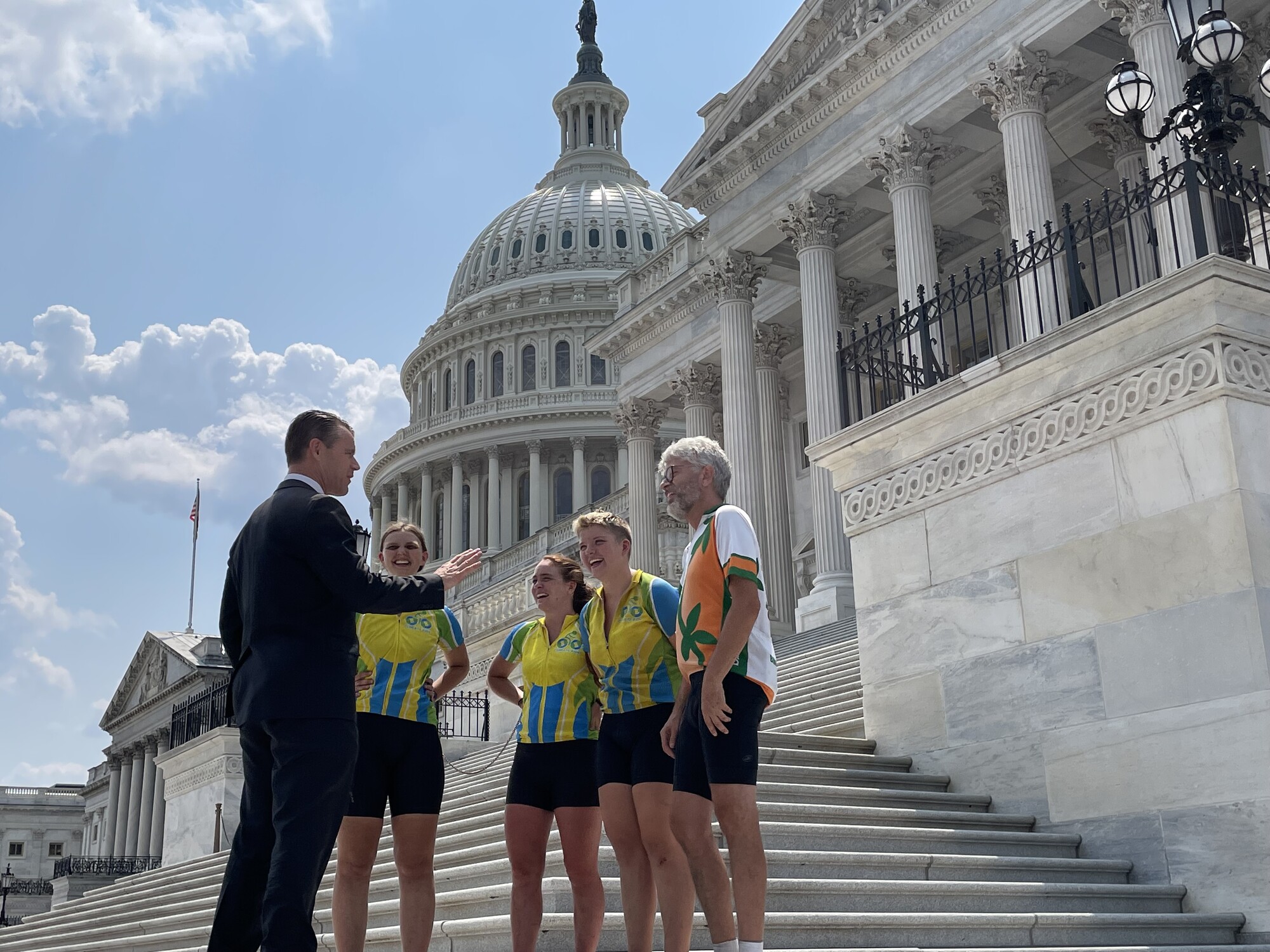 A group of cyclists standing in front of a US government building speaking to a government official