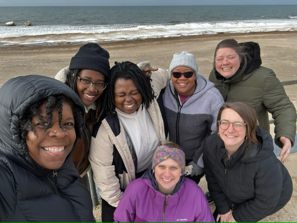 group of women smiling at camera while standing on beach