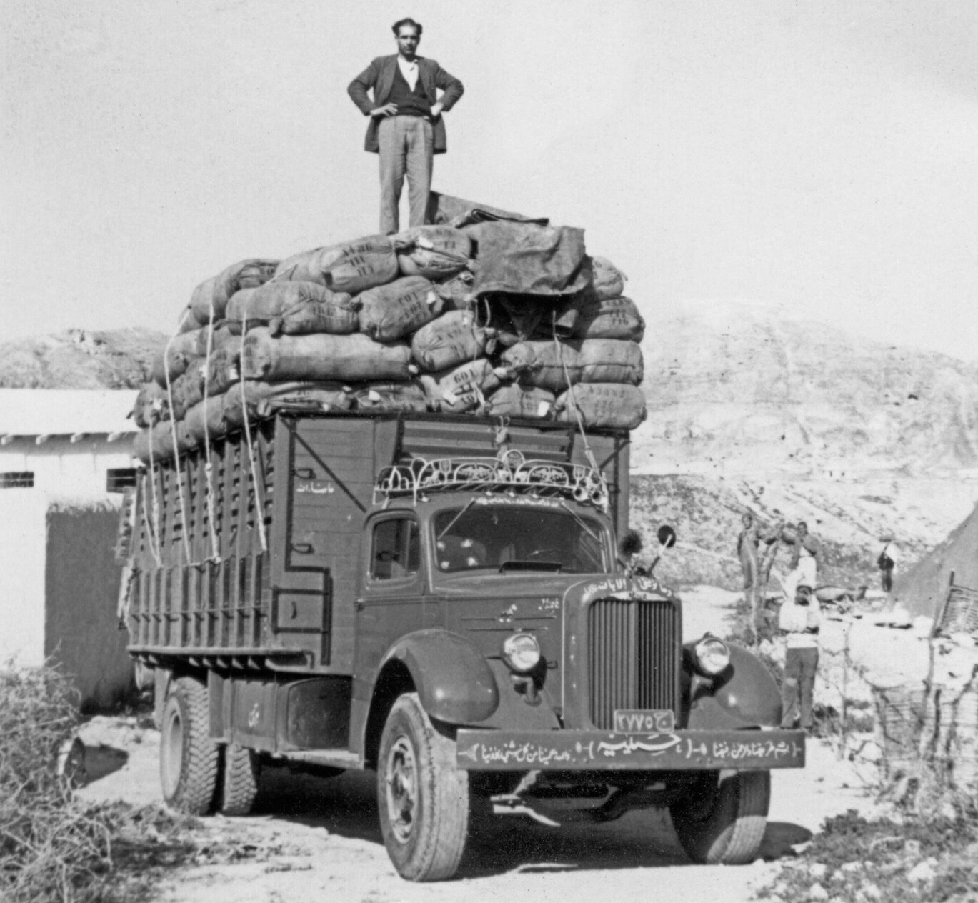 man standing on truck full of clothing bundles