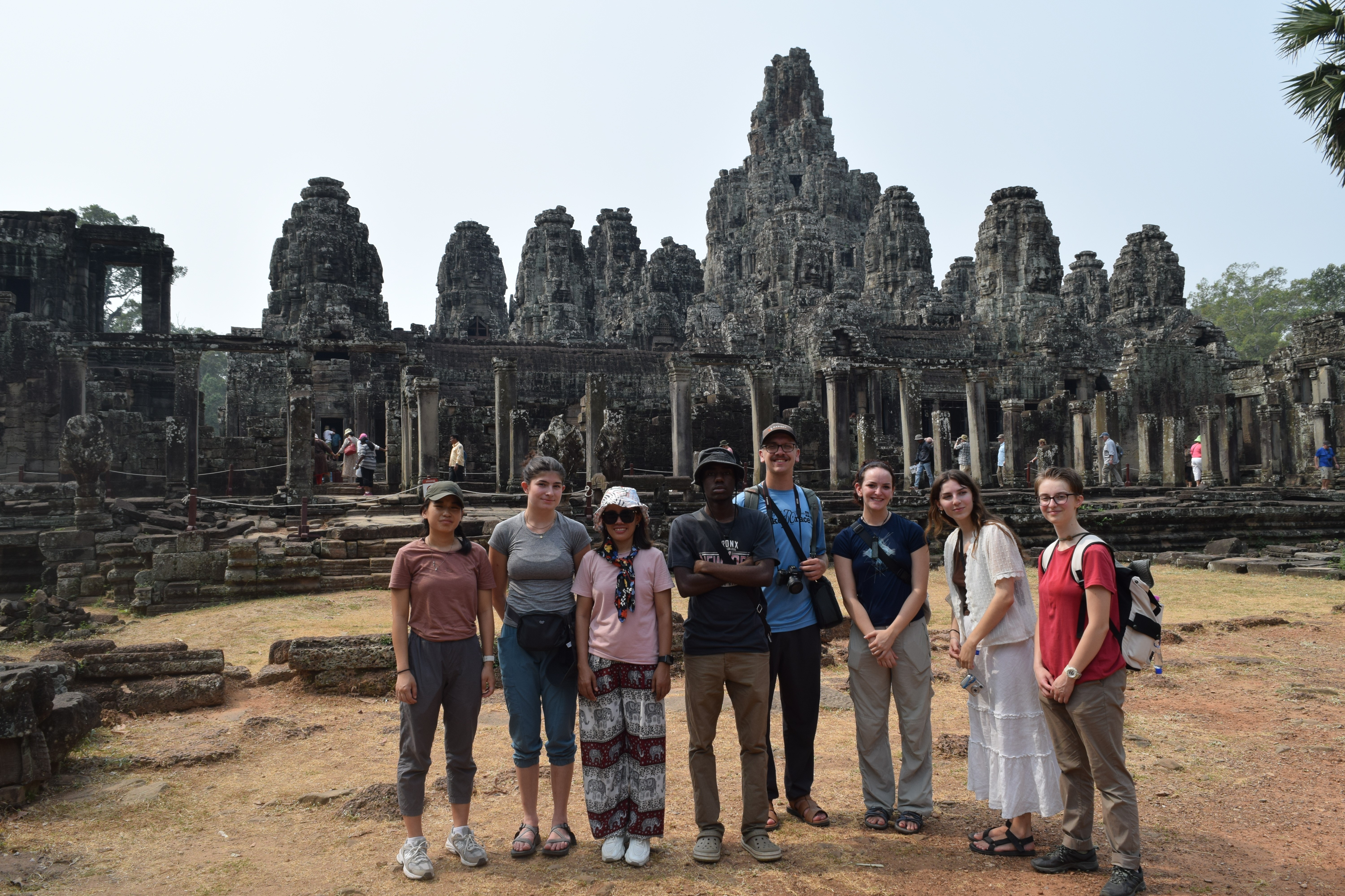 Eight young people standing in front of an ancient building