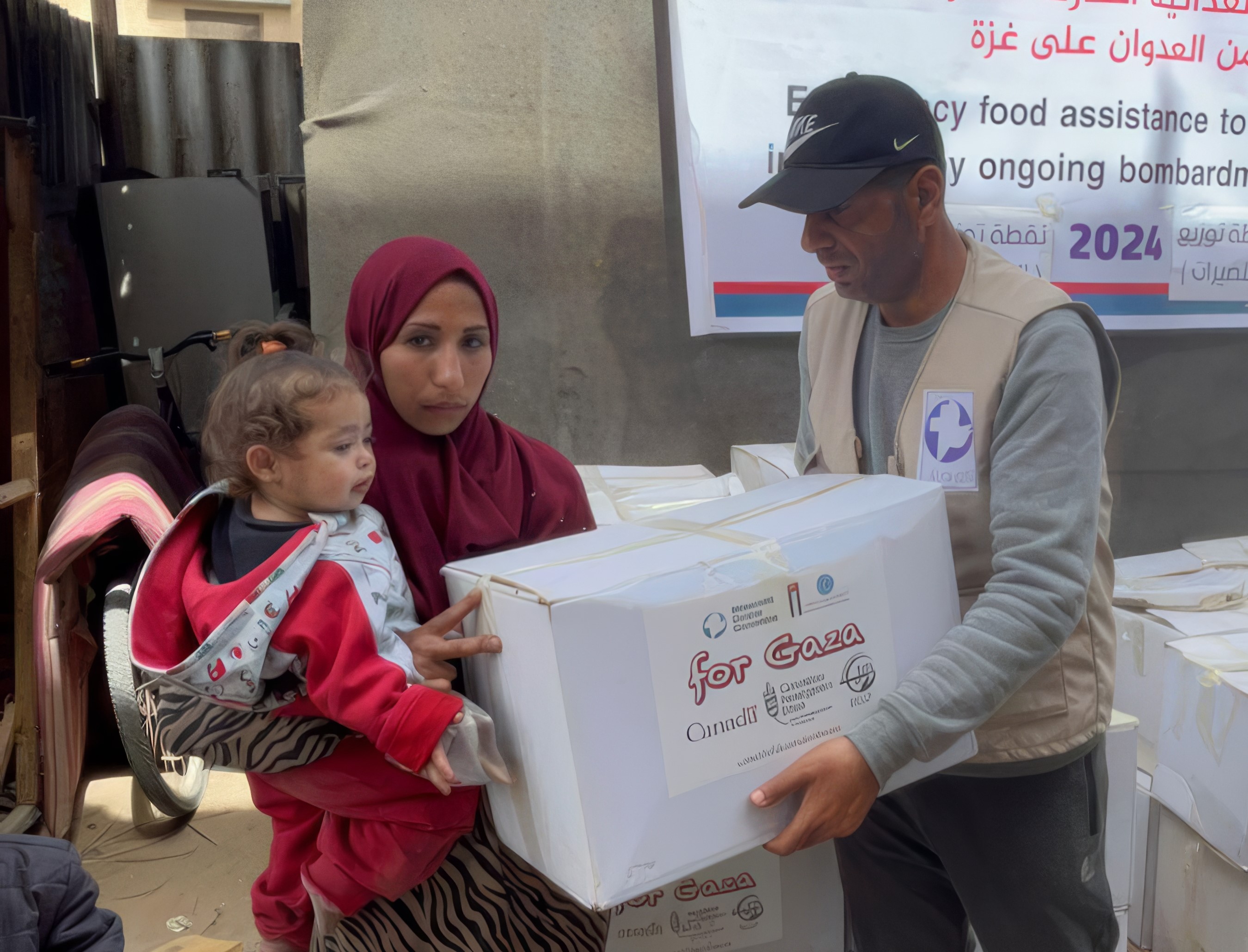 A man handing a woman and child a box of emergency relief food