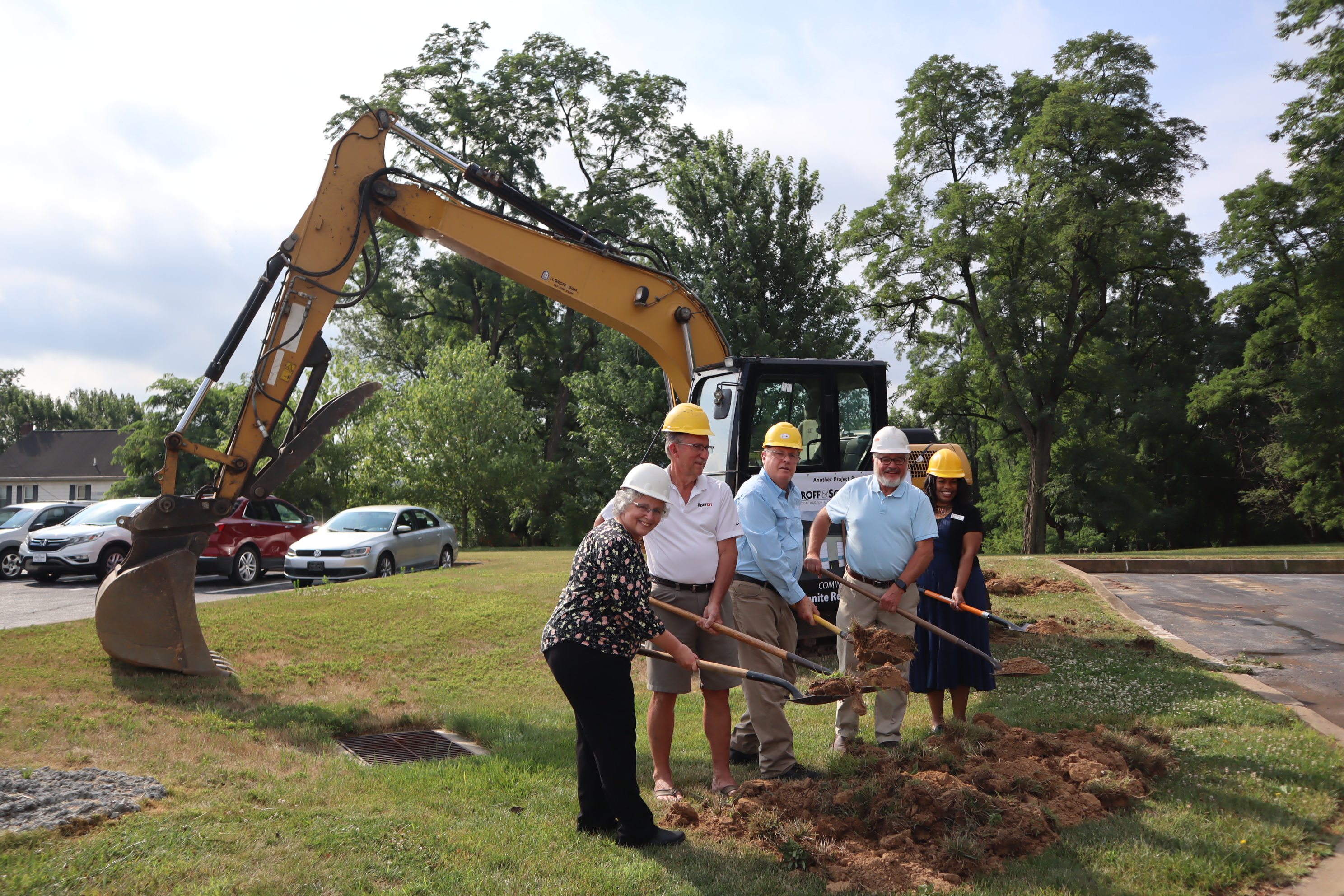 MCC staff and a volunteer lift dirt in their shovels on the site where the Material Resources Center (MRC) will be expanded.  From left to right: Carol Zook, Material Resources Center manager for MCC