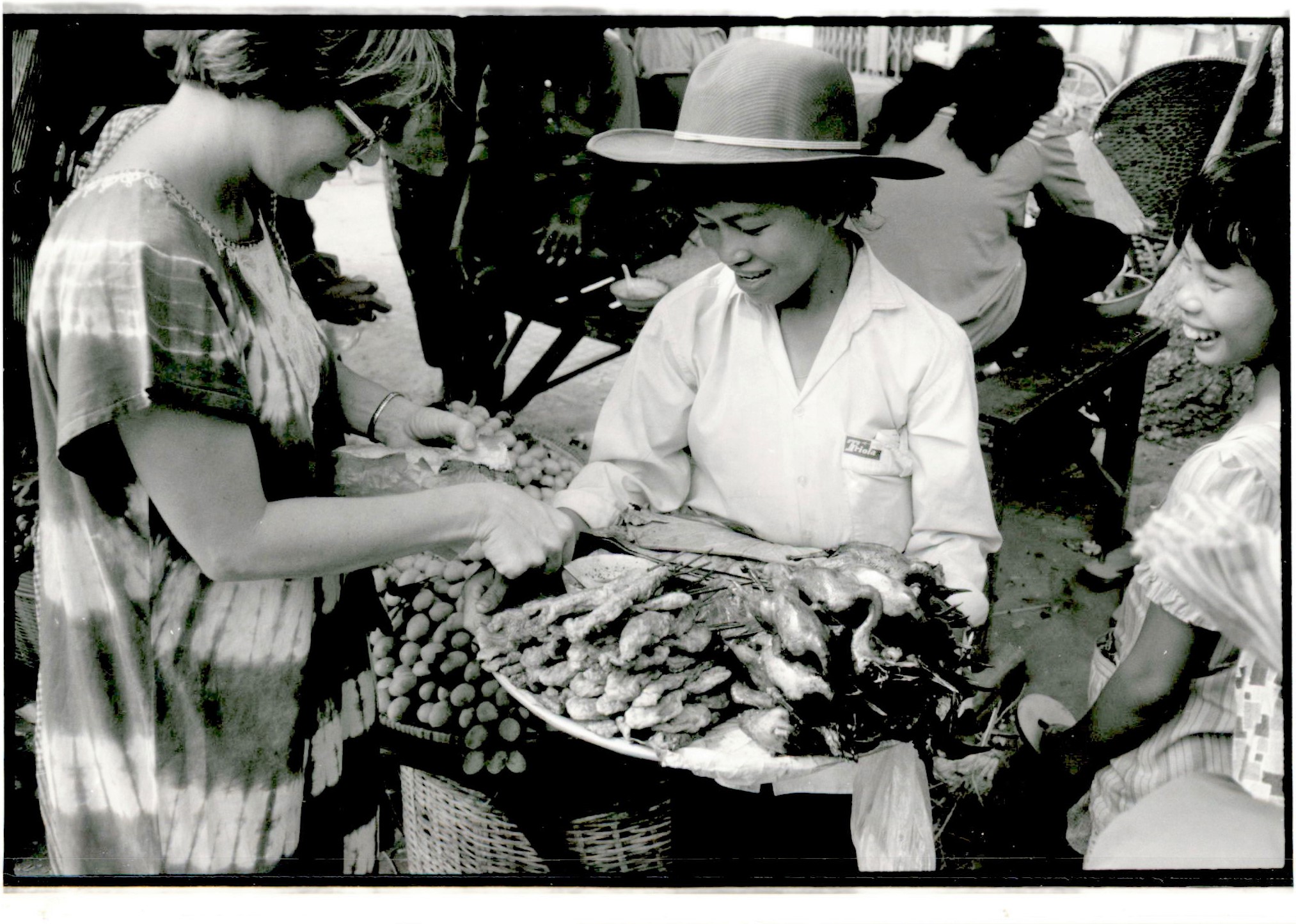 Black and white photo of MCC worker buying food from a vendor.