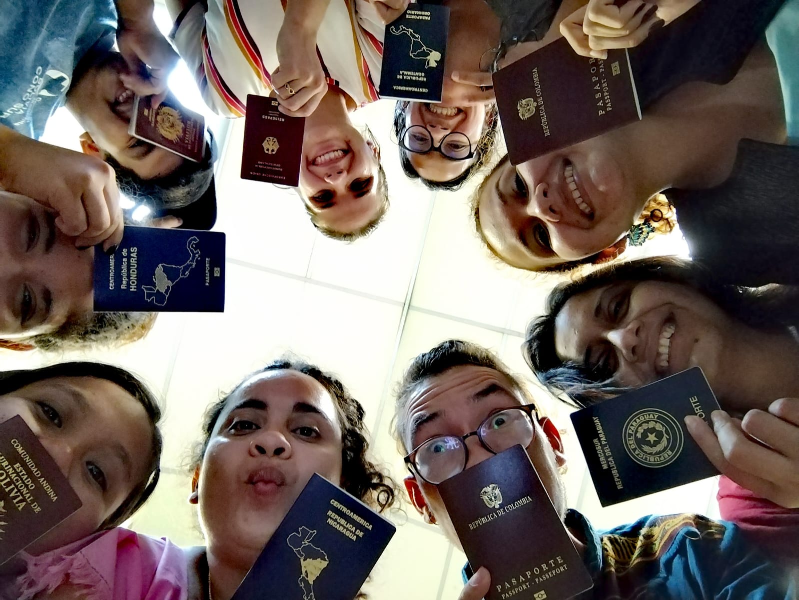 A group of students stand in a circle showing their passports, which are issued from different nations.