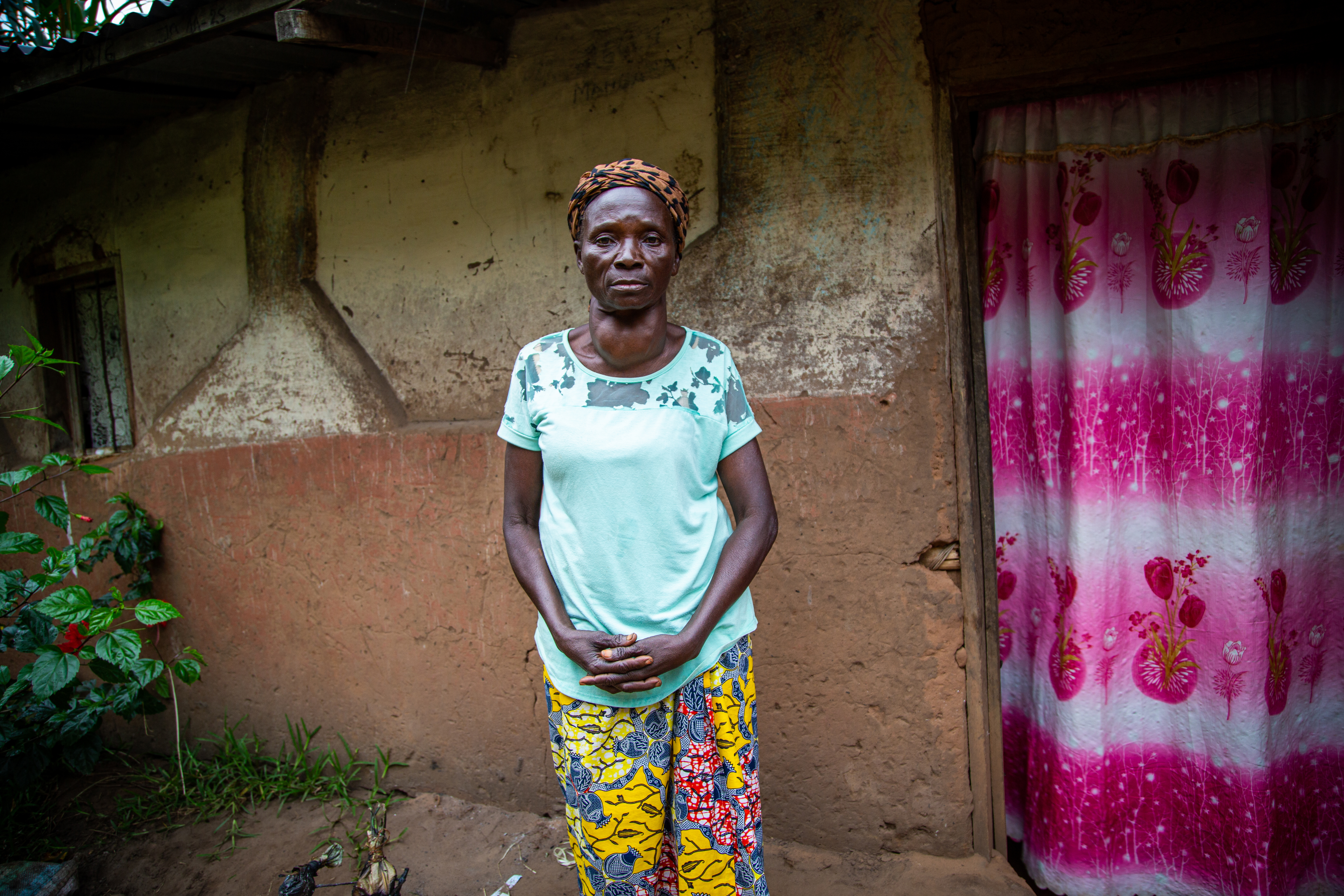  Marie Jeanne Kudimuka, 65, stands outside her home.