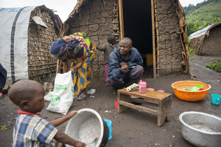 a family shares an outdoor meal near their mud-brick home