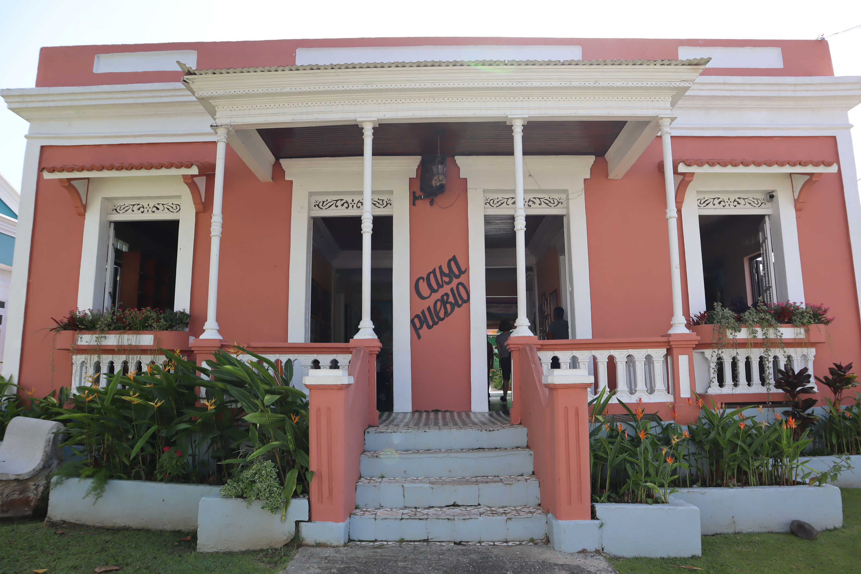 a pink house with white trim and a large front porch