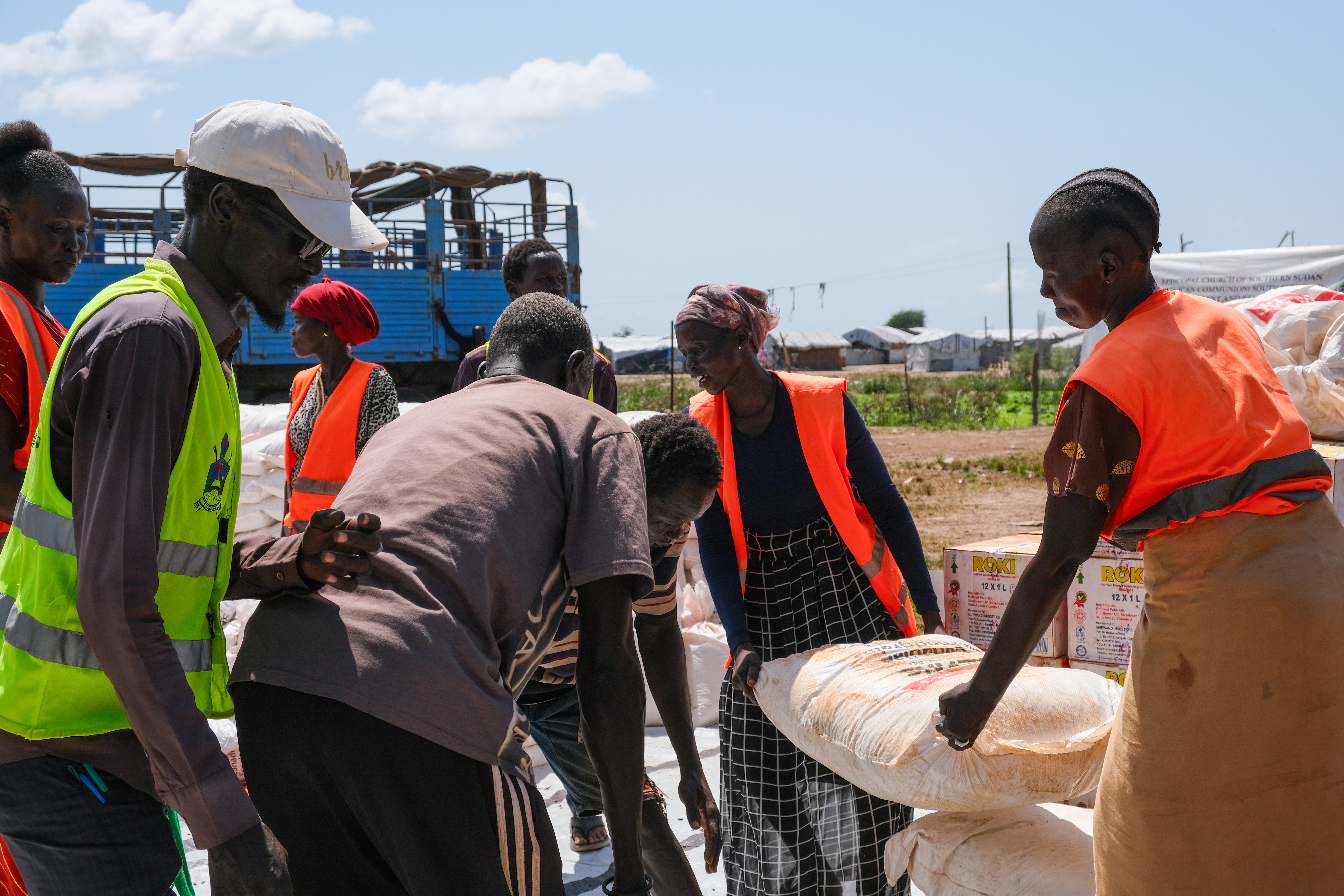 olunteers work to move the bags of sorghum off the truck, and organize them with the other food items for program participants to collect. MCC partner Episcopal Church of South Sudan – South Sudanese Development and Relief Agency (ECSS-SSUDRA) employs volunteers to help at the distribution site.