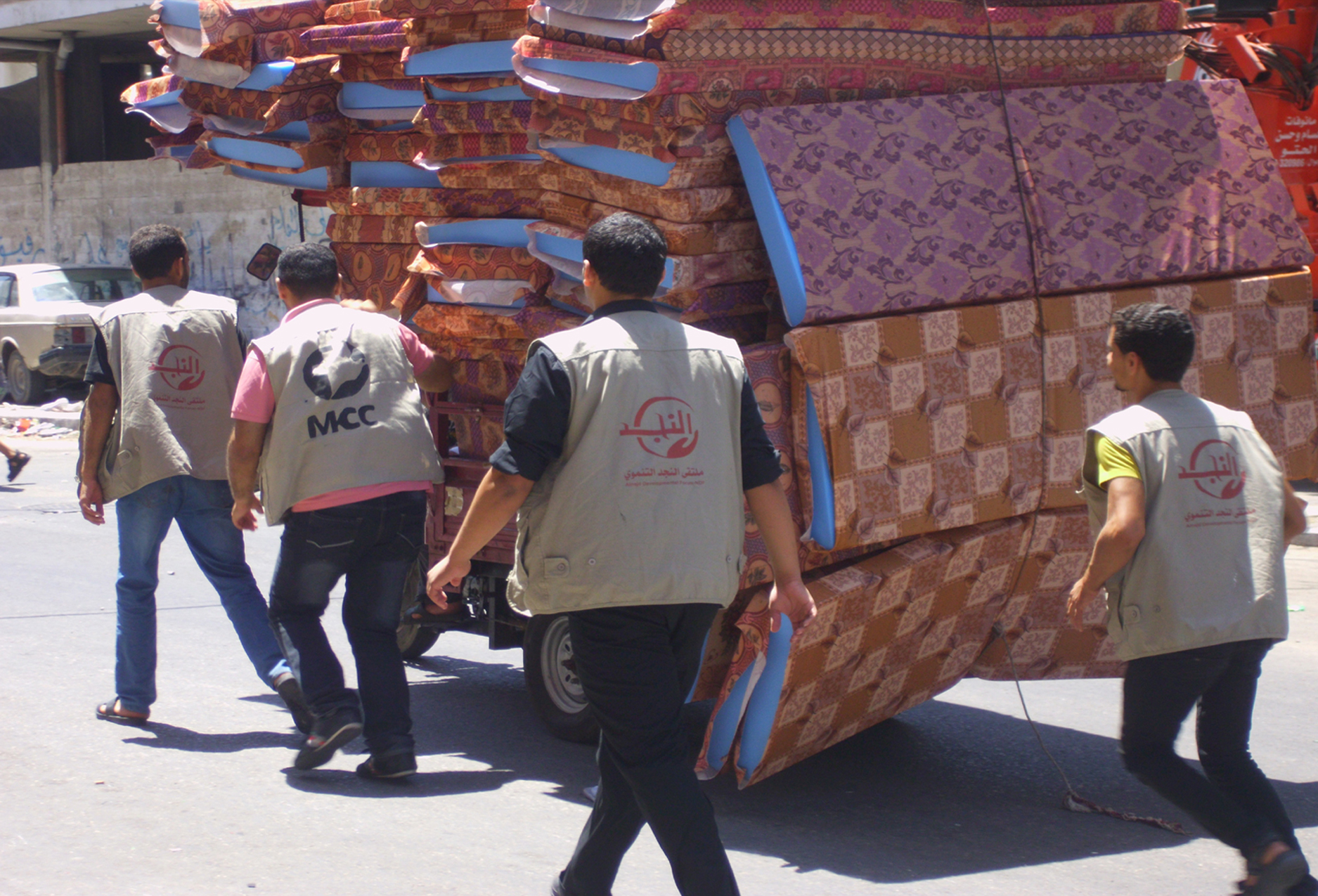 men escorting large cartload of mattresses