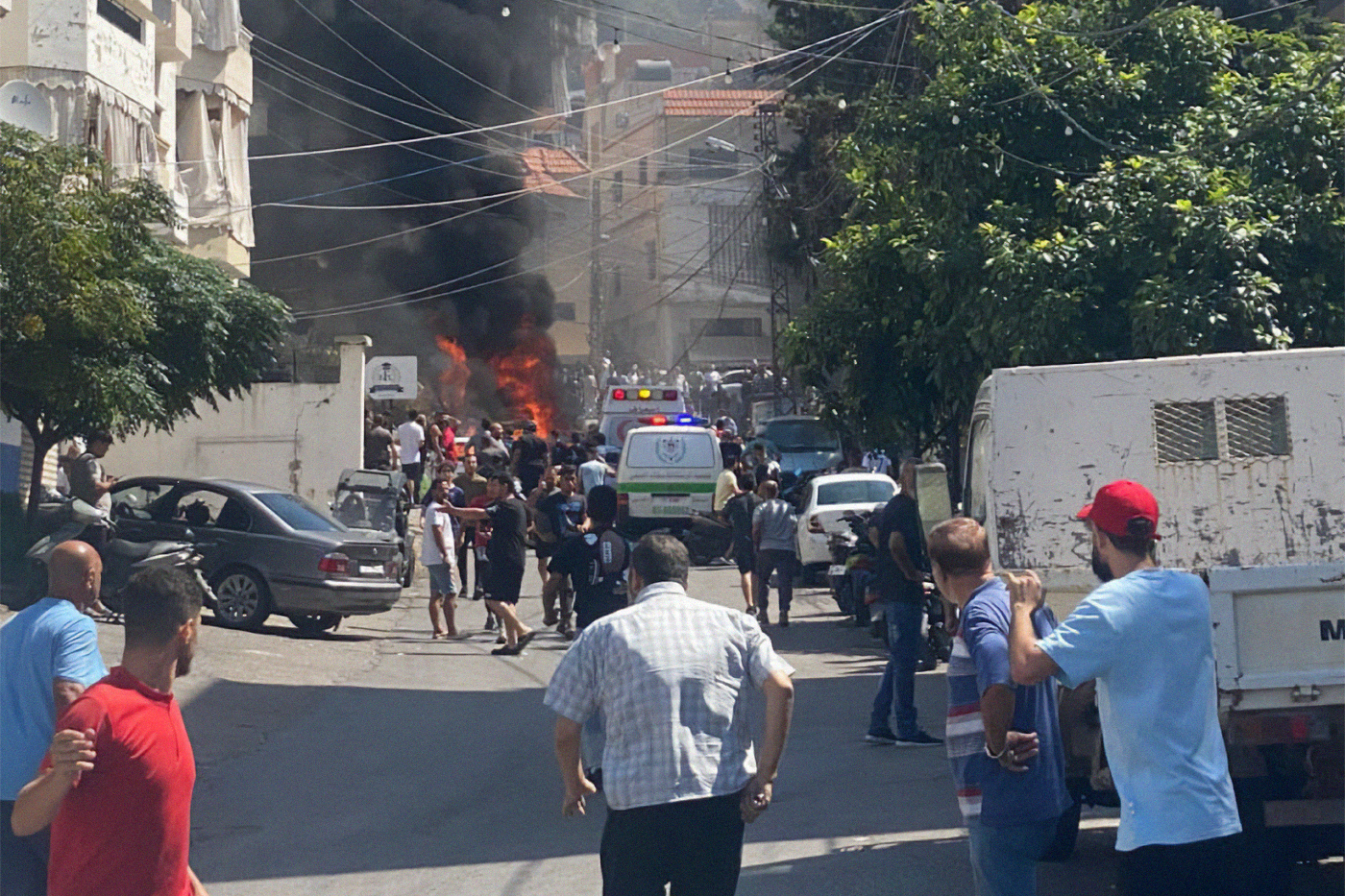 A group of spectators view a fire burning in the distance.