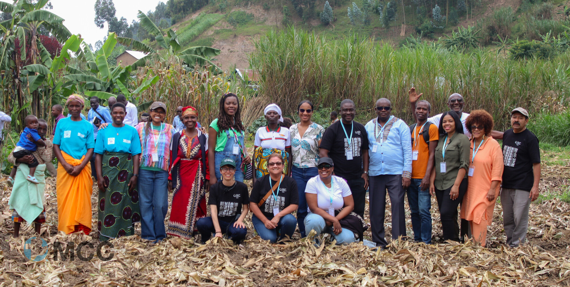 group of men and women standing in a row in front of tropical greenery