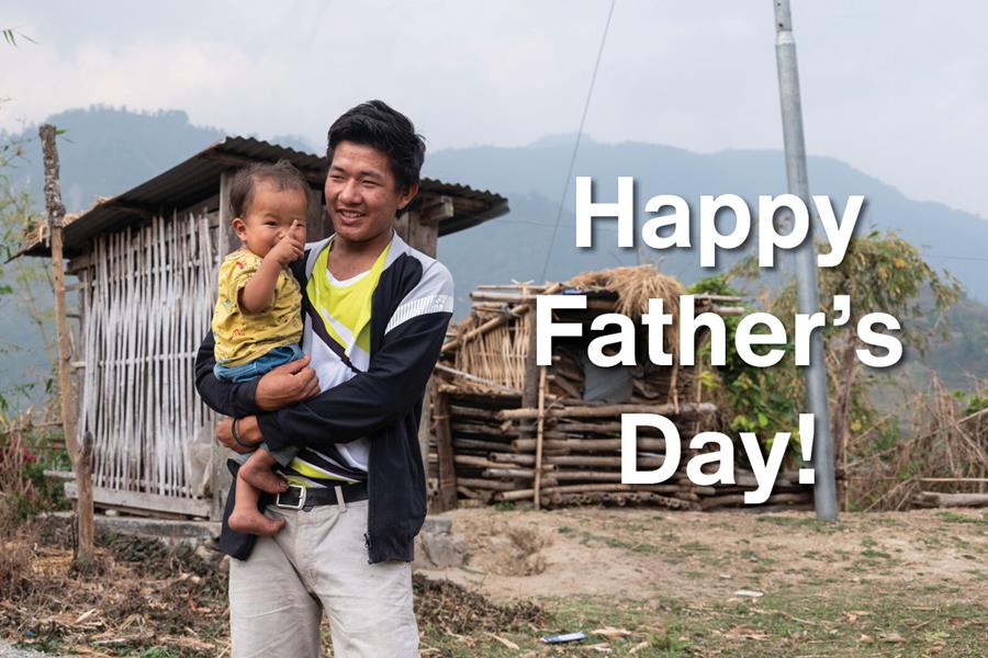 A smiling man holding a child with the words "Happy Father's Day!"