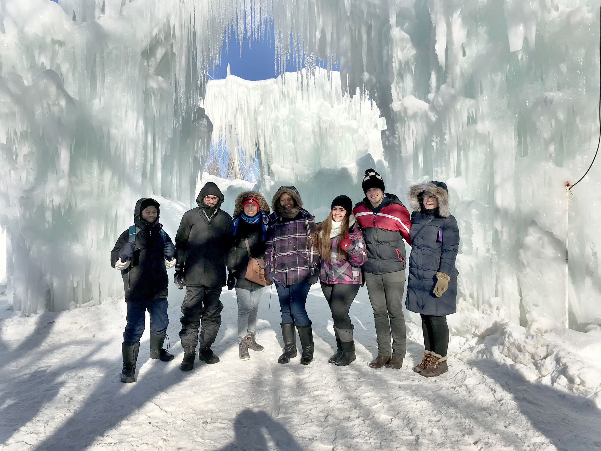 Seven people in winter clothing stand together, surrounded by walls of ice.