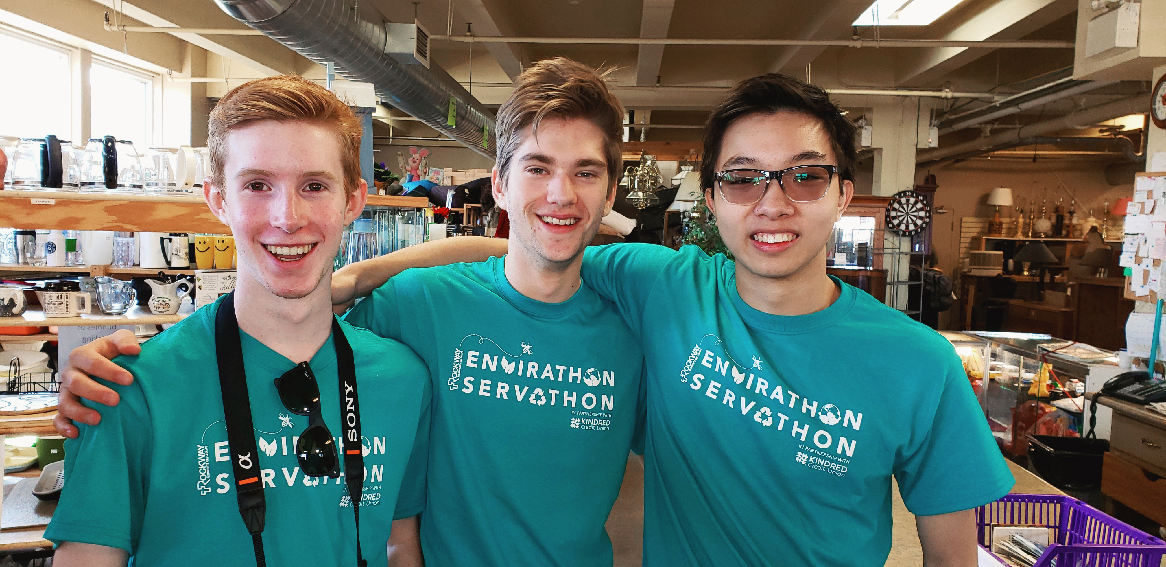 Three male youth smile at the camera wearing green t-shirts.