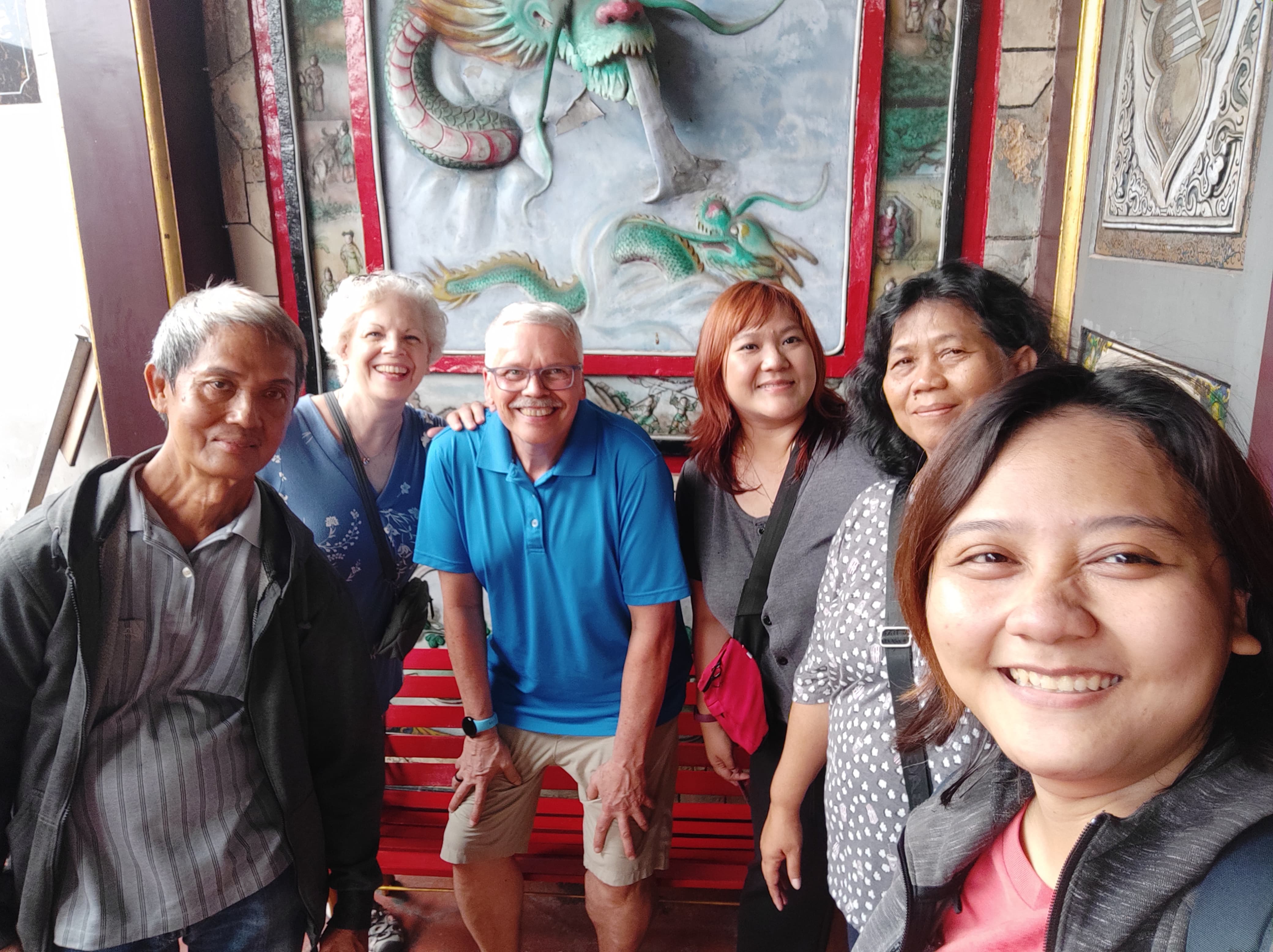 A U.S. couple stands with four other people in front of a mural with a dragon on it.