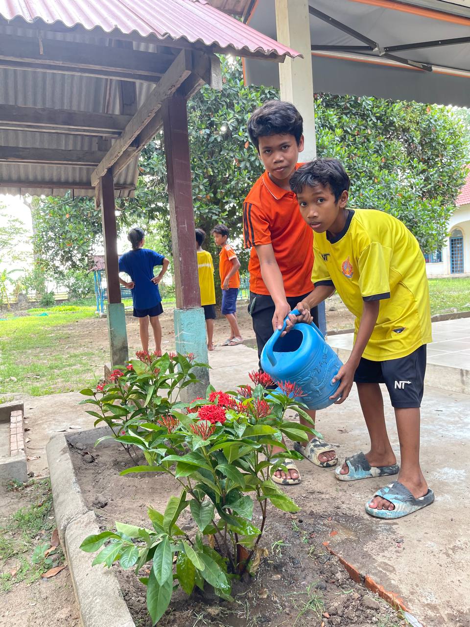 Two young boys watering plants.