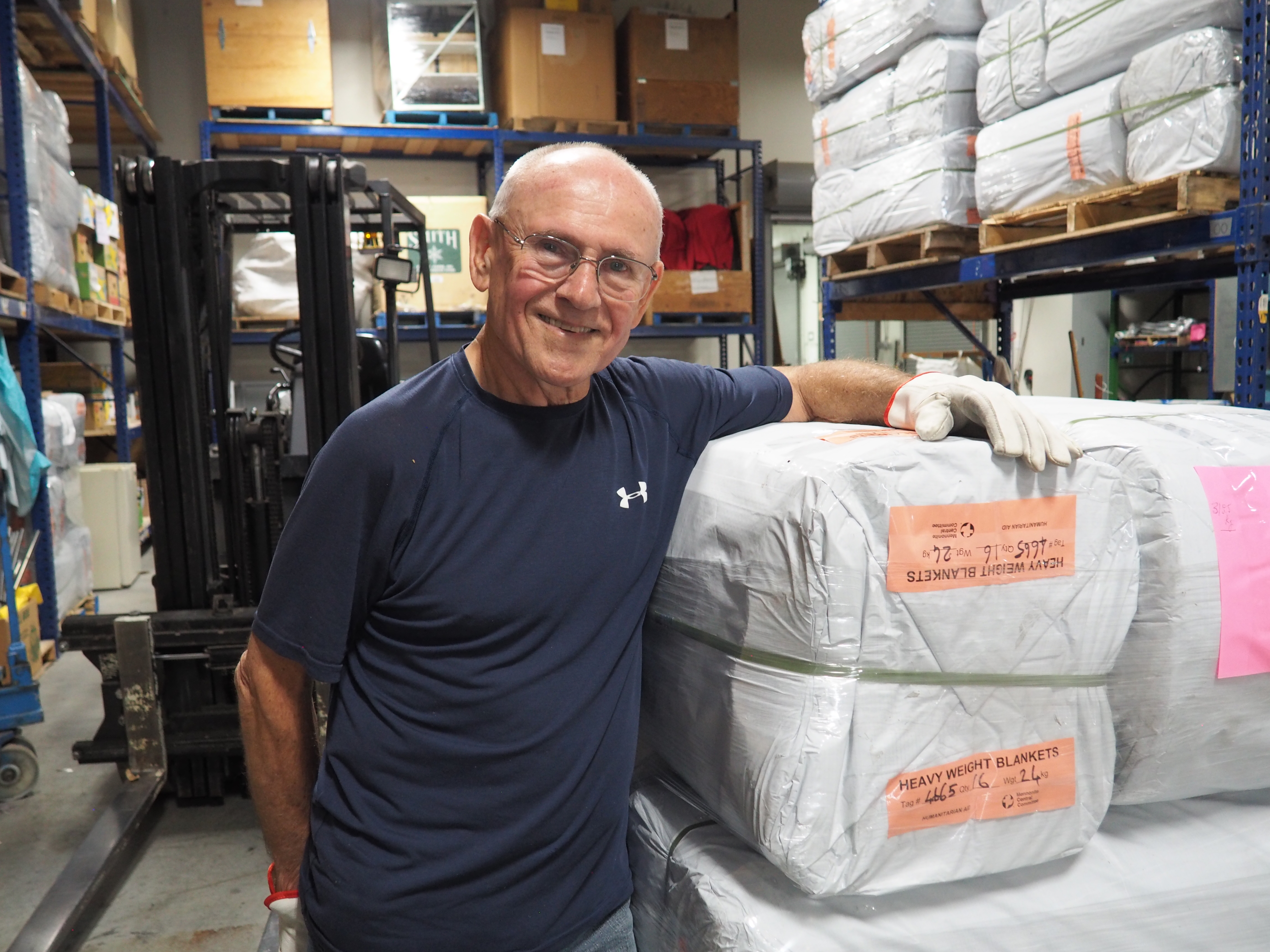 Ken Kohlmeier standing with supplies in an MCC warehouse in British Columbia, Canada.