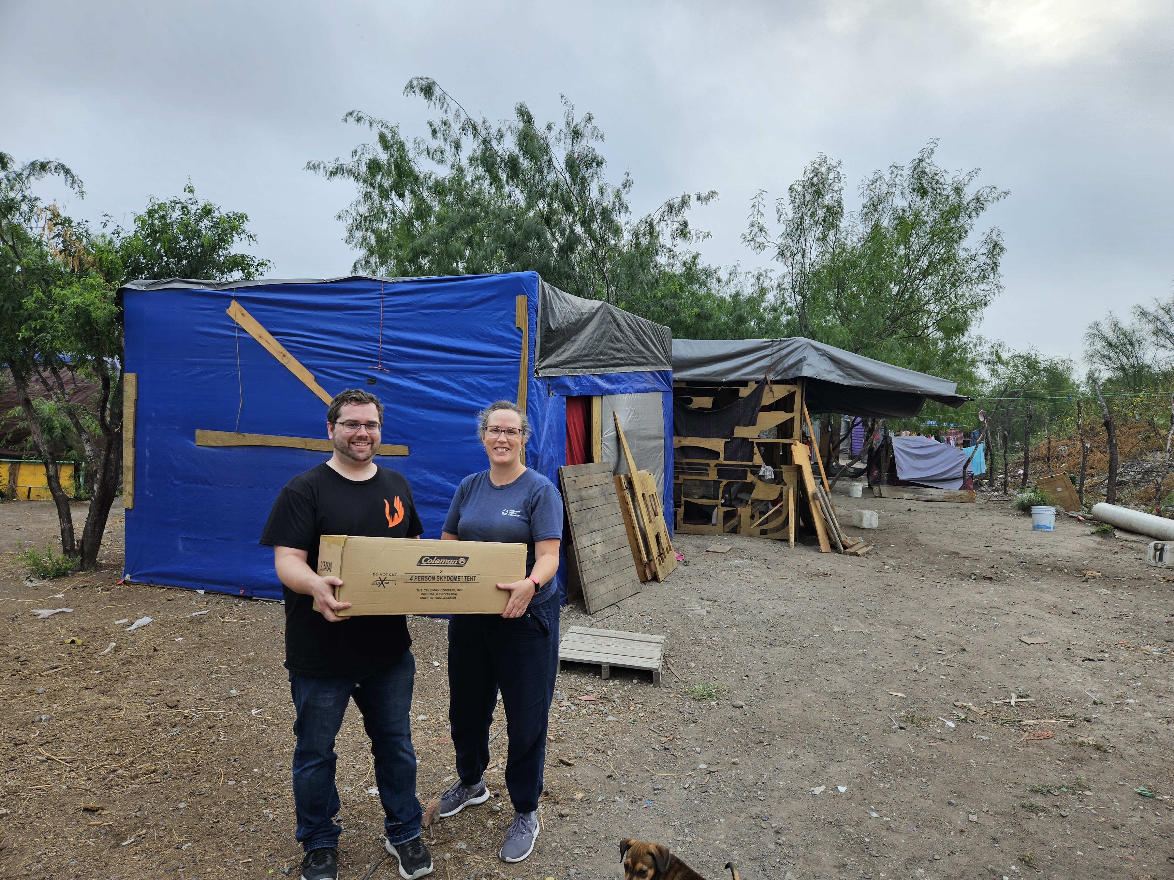 a man and woman hold package in front of tents