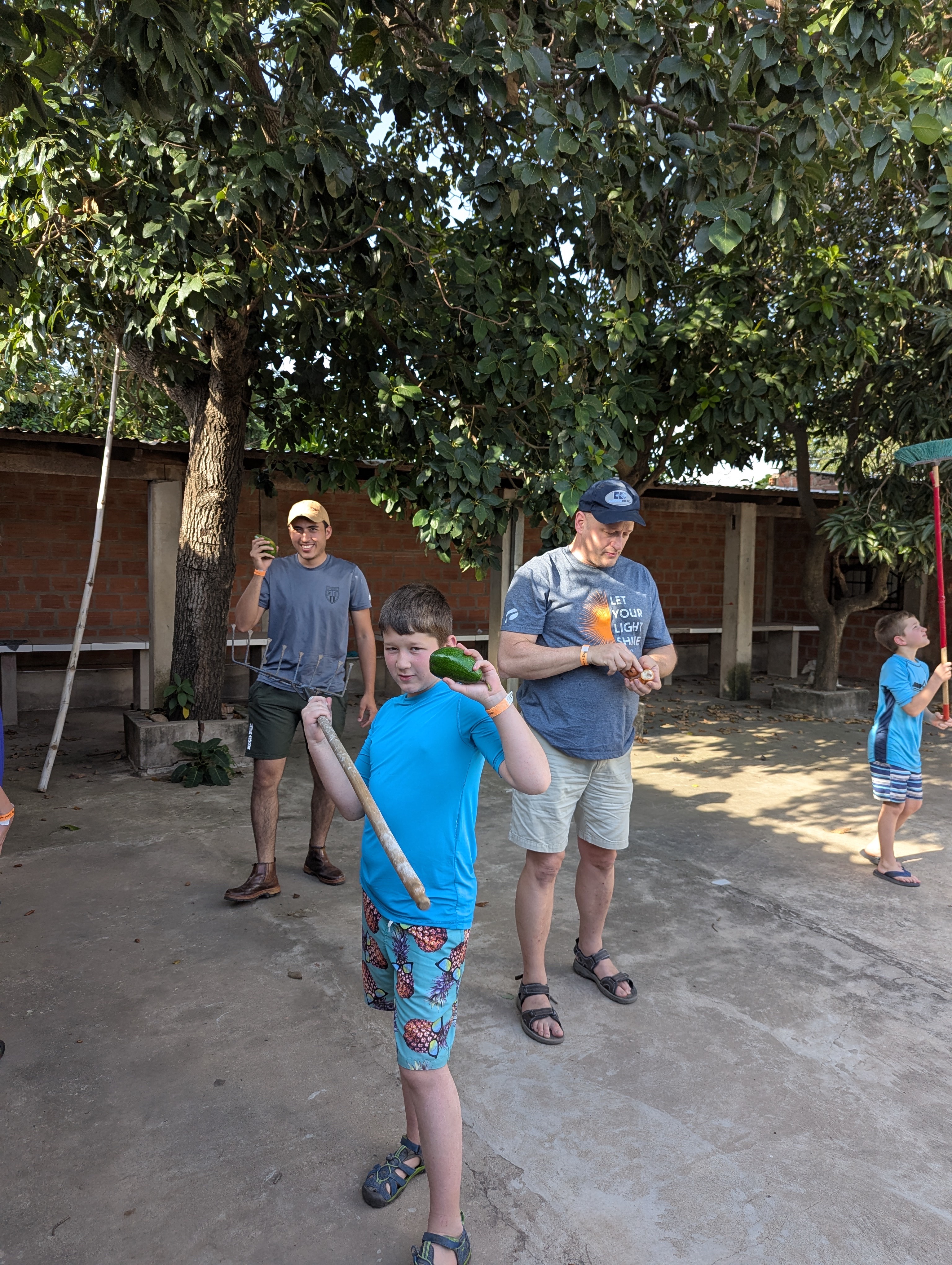people standing outside under trees holding fruit