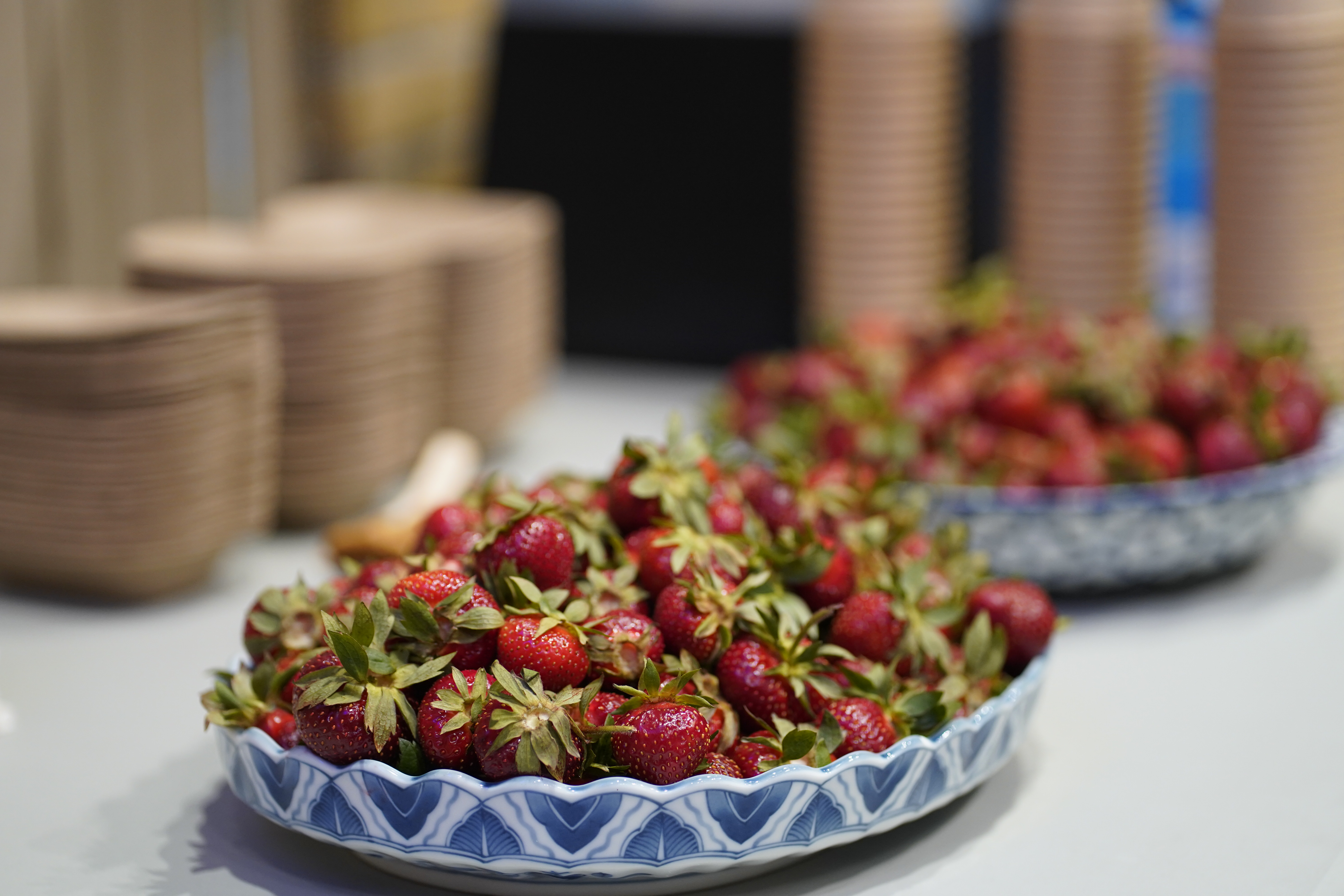 Earthenware plates with blue design piled high with strawberries sit on a table