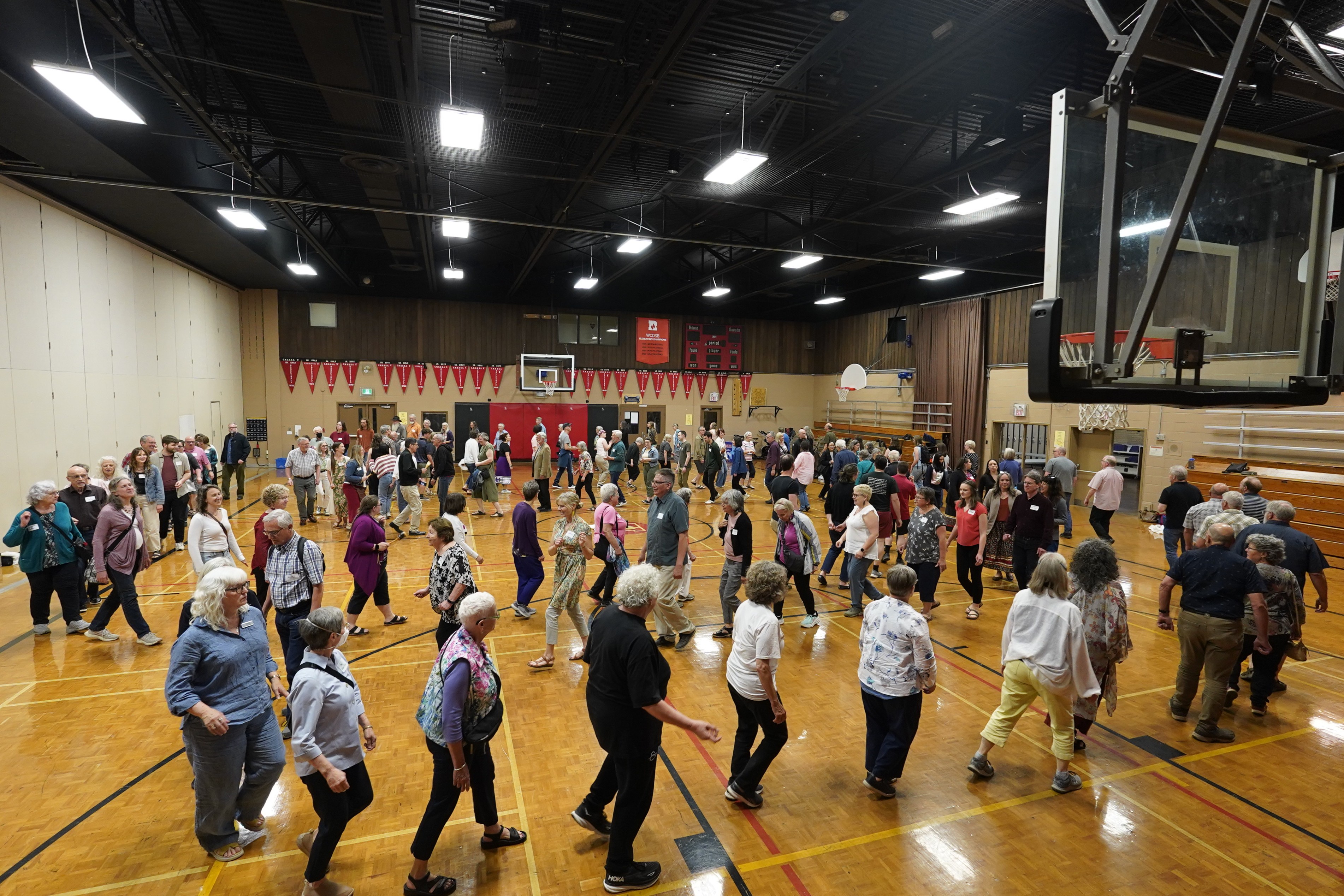 A long, winding group of people of all ages wind around a gymnasium.