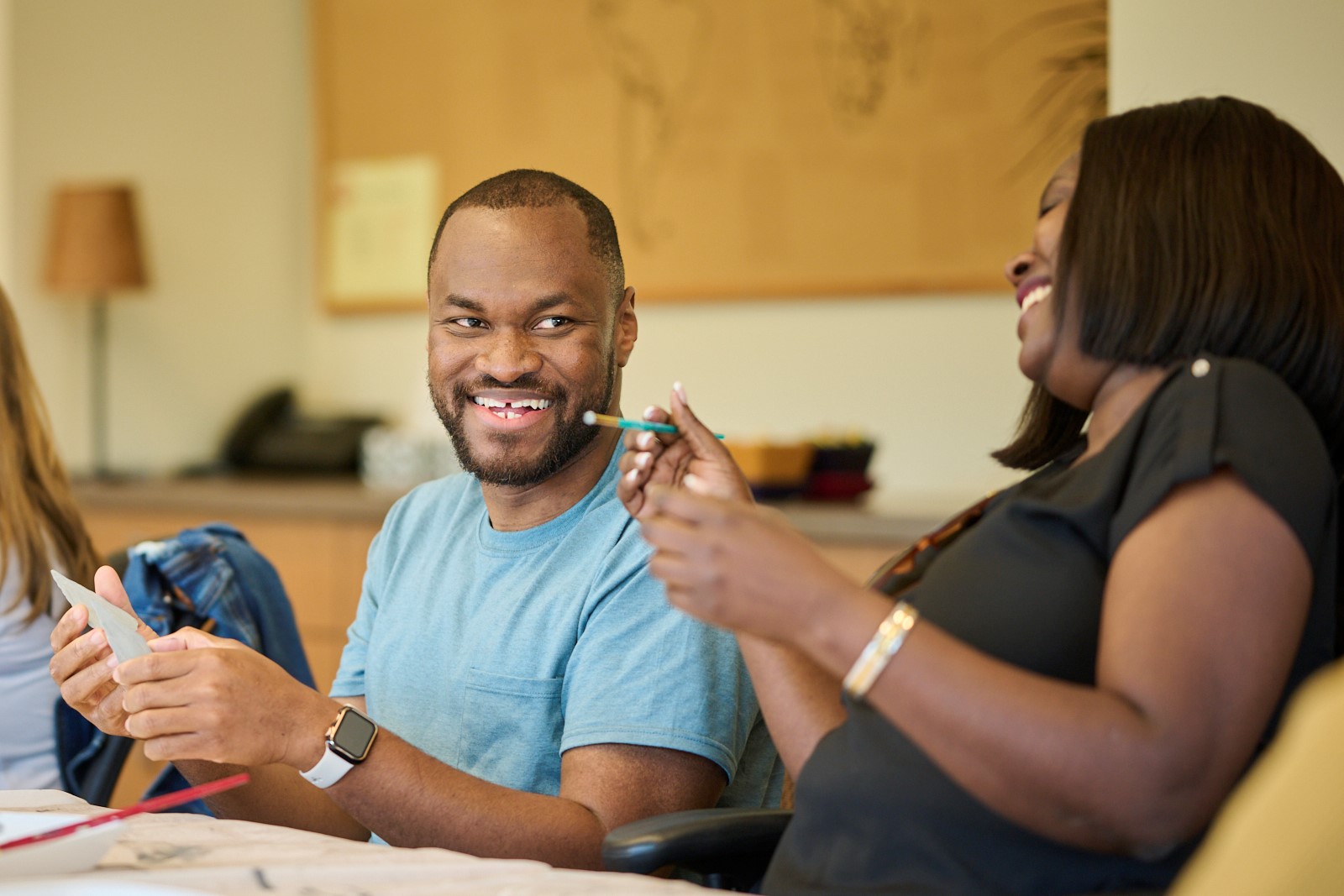 Kojo Kyei on the left laughing while painting, Sarah Njeri on the right