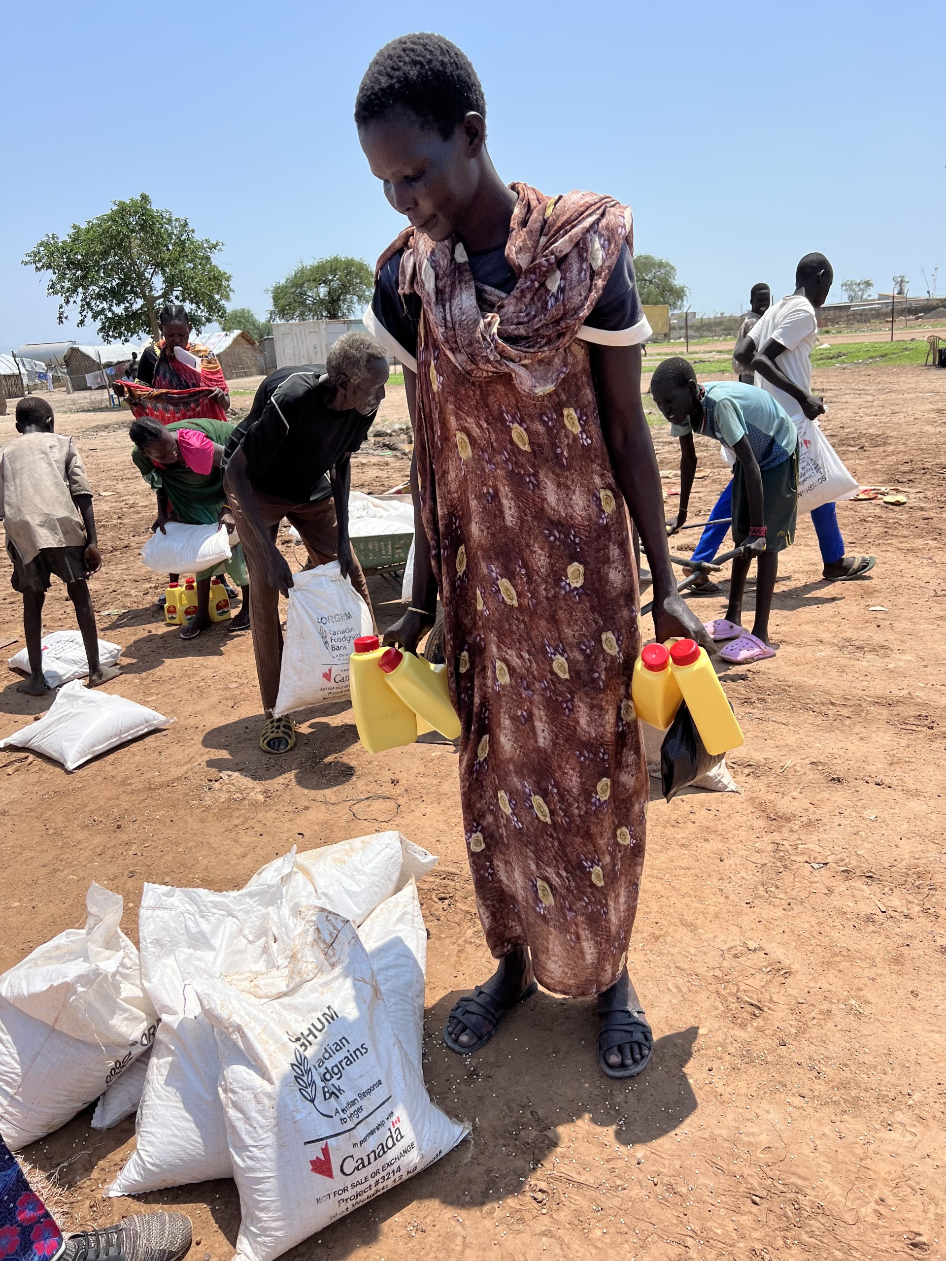 A woman from South Sudan named Martha collects food from a distribution area.