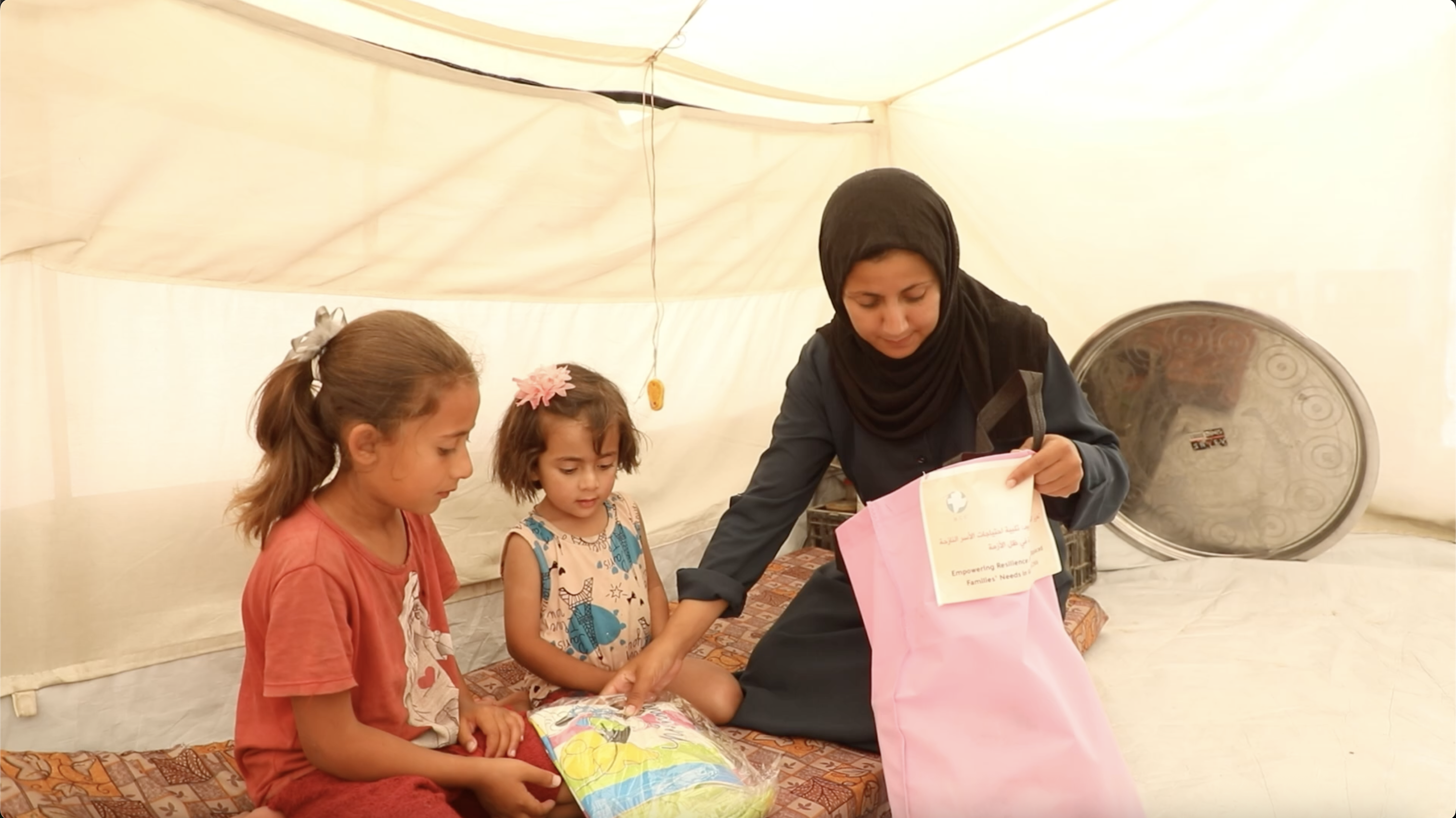 Nisma opens the care package and hands clothing to her two children.