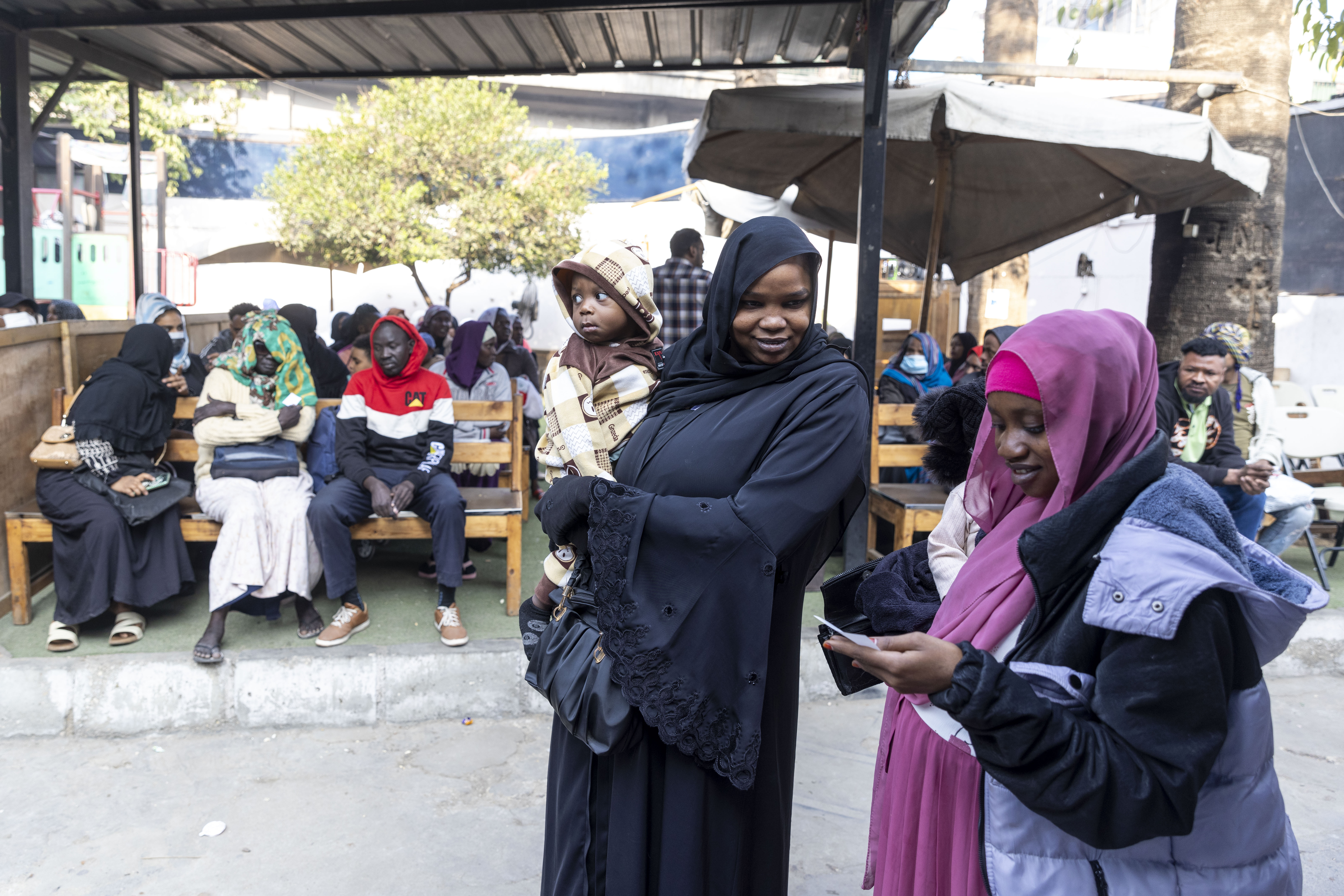 Two refugees in Cairo, Egypt stand in front of a group of people. 