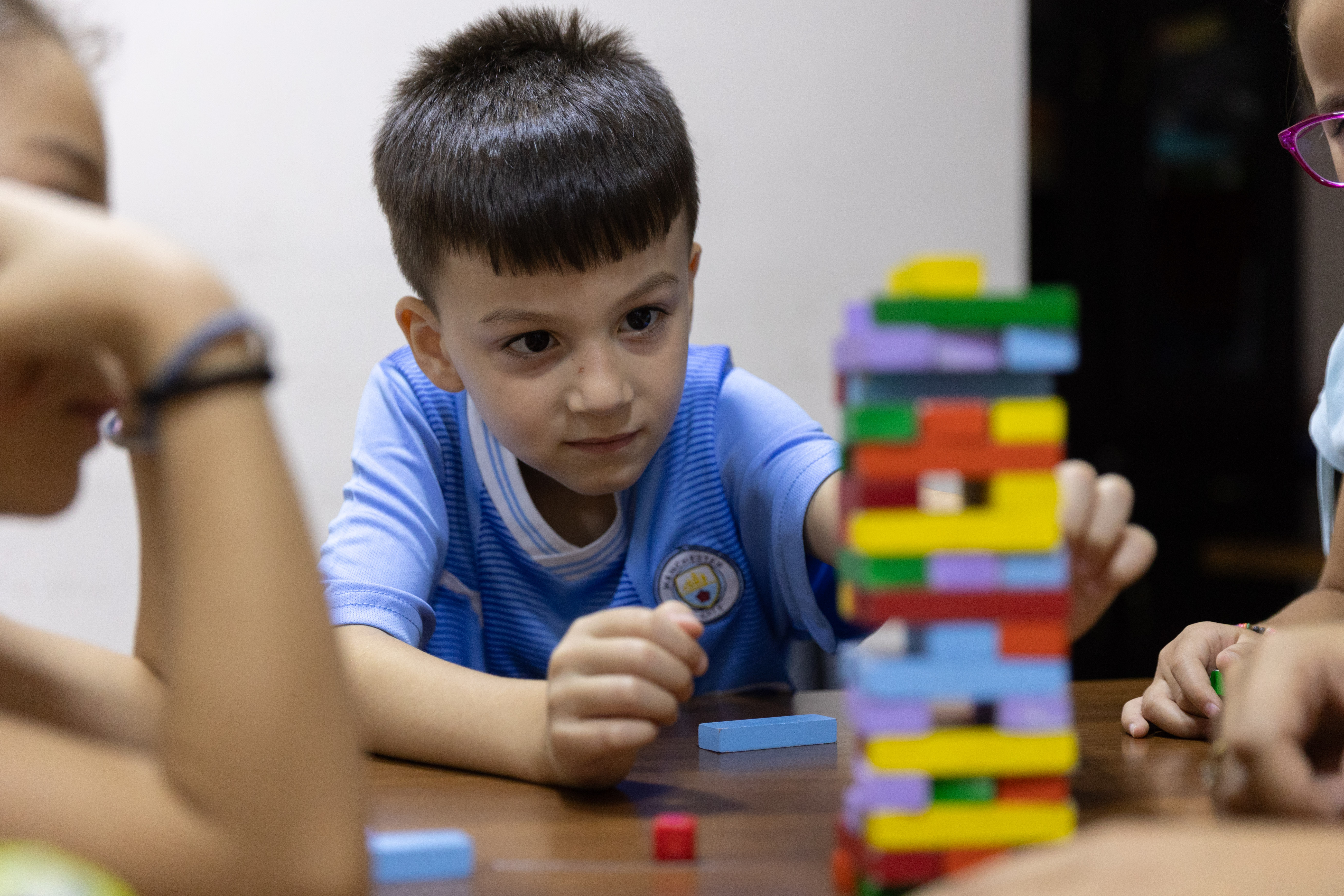 A child in Syria plays with Jenga blocks at a table of his peers.