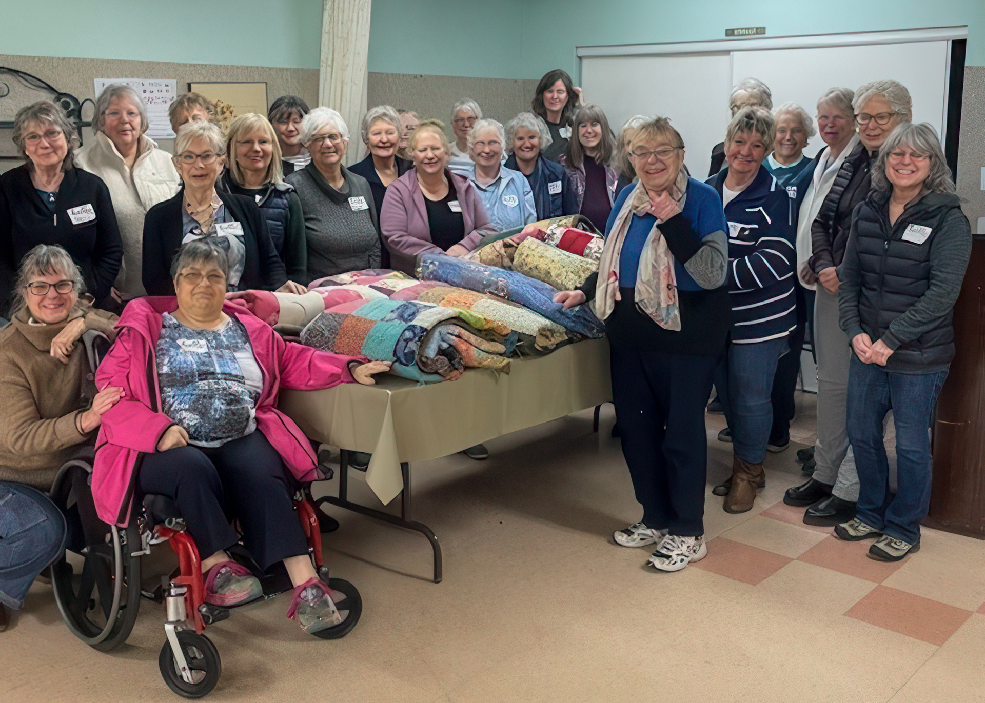 A group of volunteers poses around handmade comforters at Black Creek United Mennonite Church in British Columbia, Canada