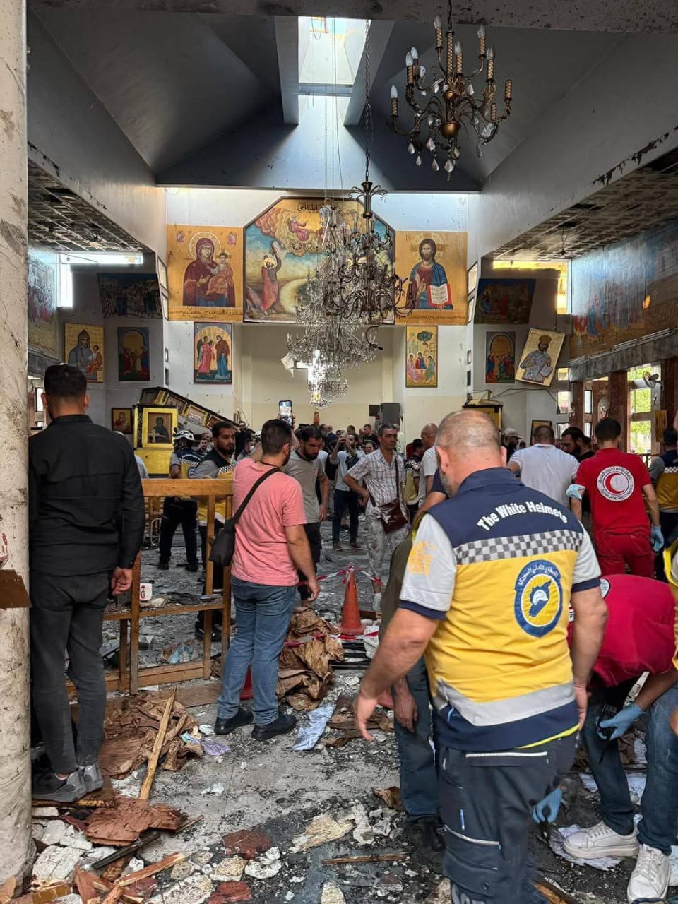 people look at damage of bombed church in Syria