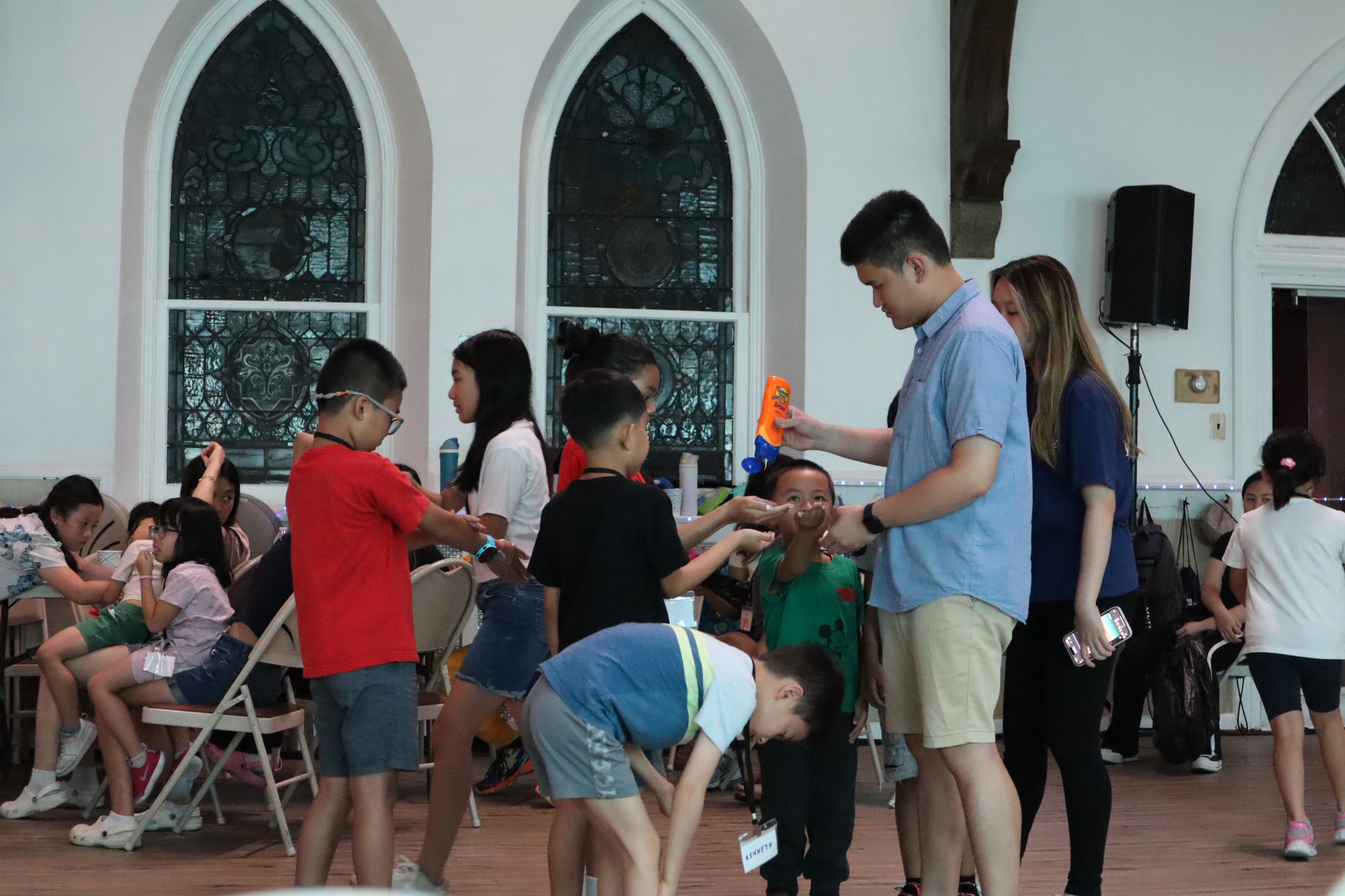 a young adult distributes sunscreen to children