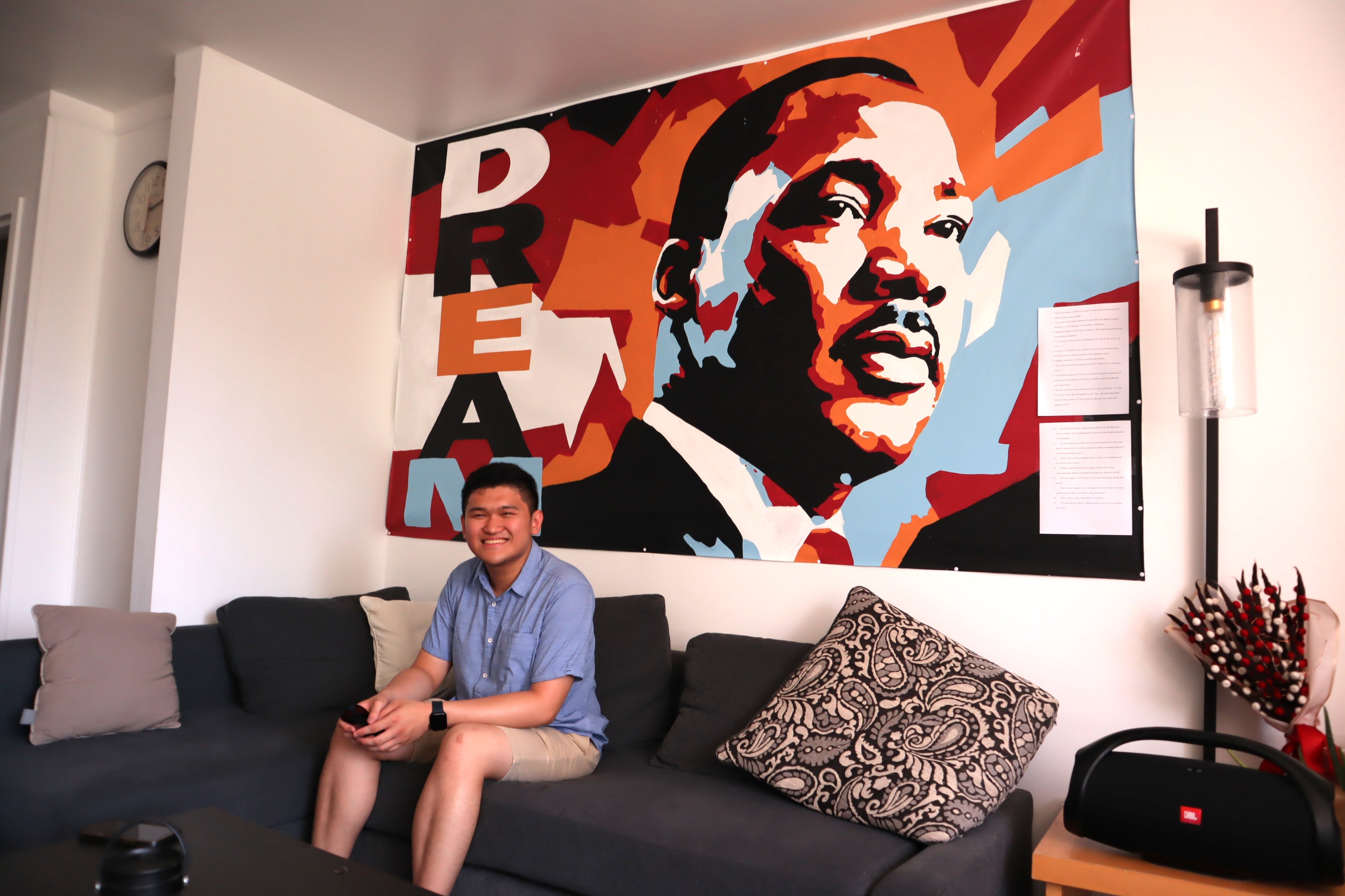 young adult sits on a sofa in front of an MLK banner