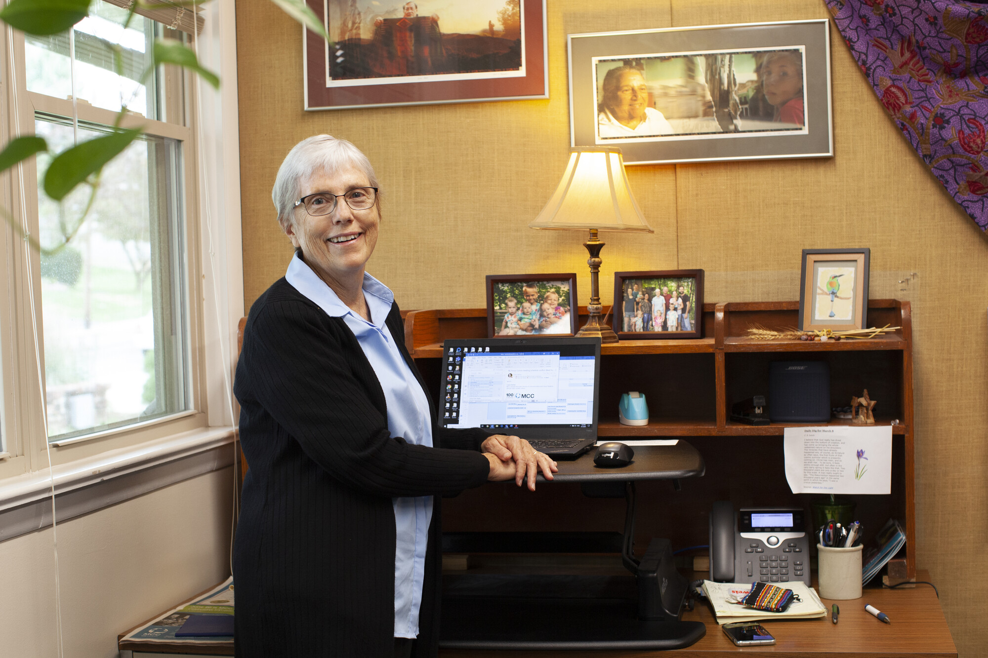 woman sitting in front of desk with a computer and family pictures in the background