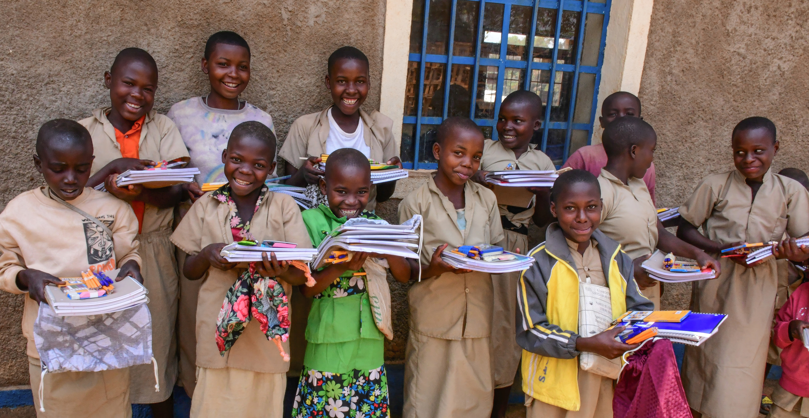 children standing in two lines holding school kits