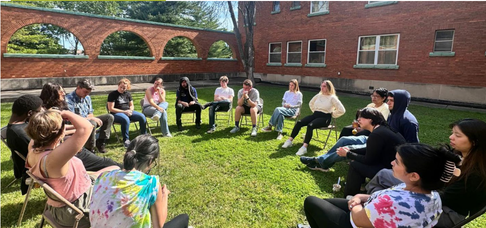 Group of young adults sit in a circle outdoors