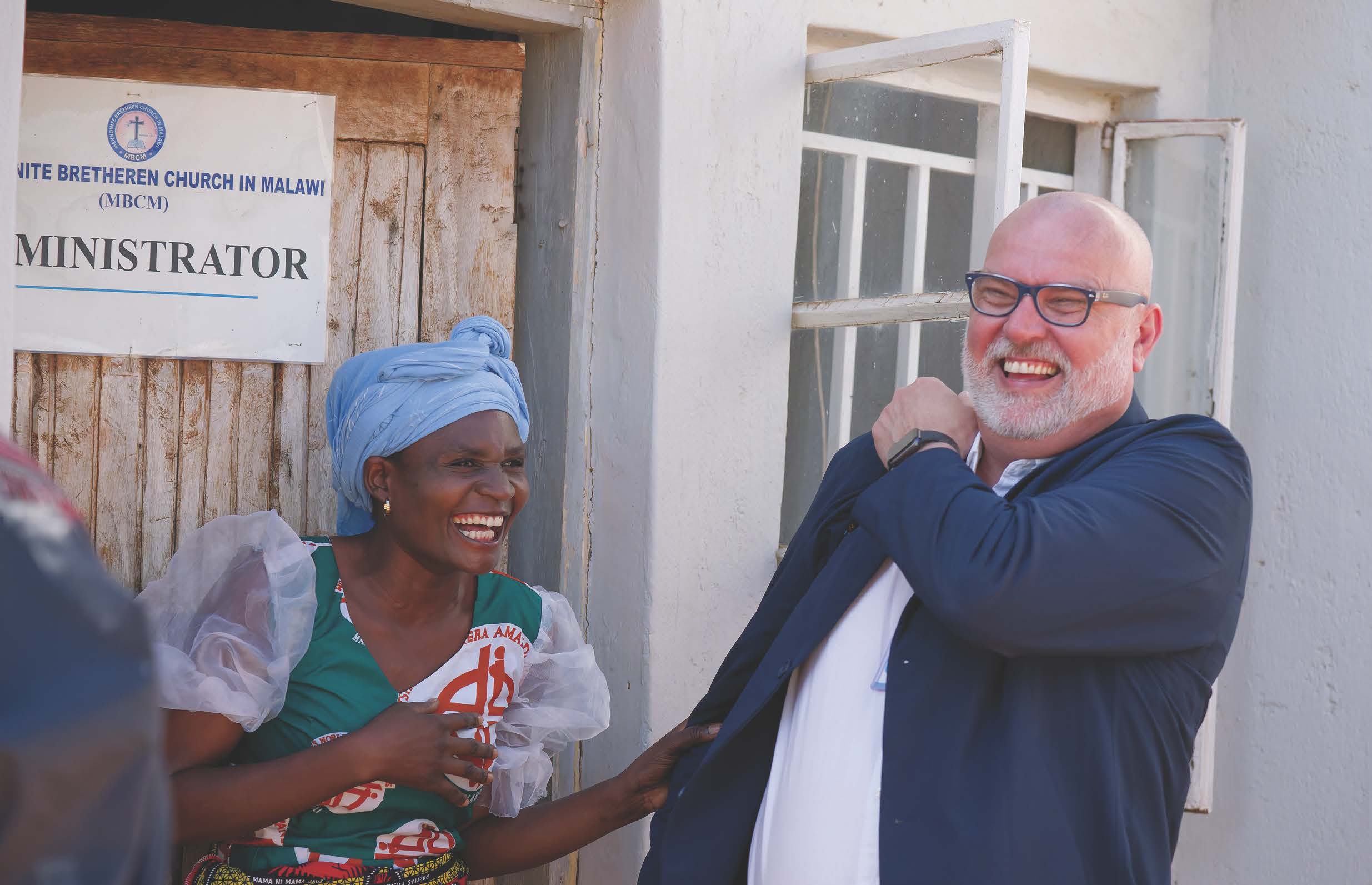 A woman and man laughing in front of a building